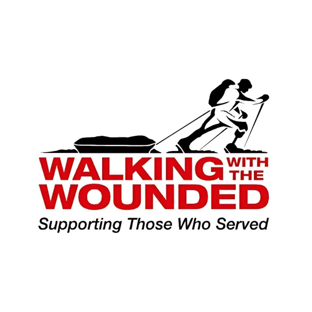 Silhouette of a soldier pulling a wounded comrade on a sled, with bold red and black text that reads 'Walking with the Wounded' and a smaller tagline 'Supporting Those Who Served'.