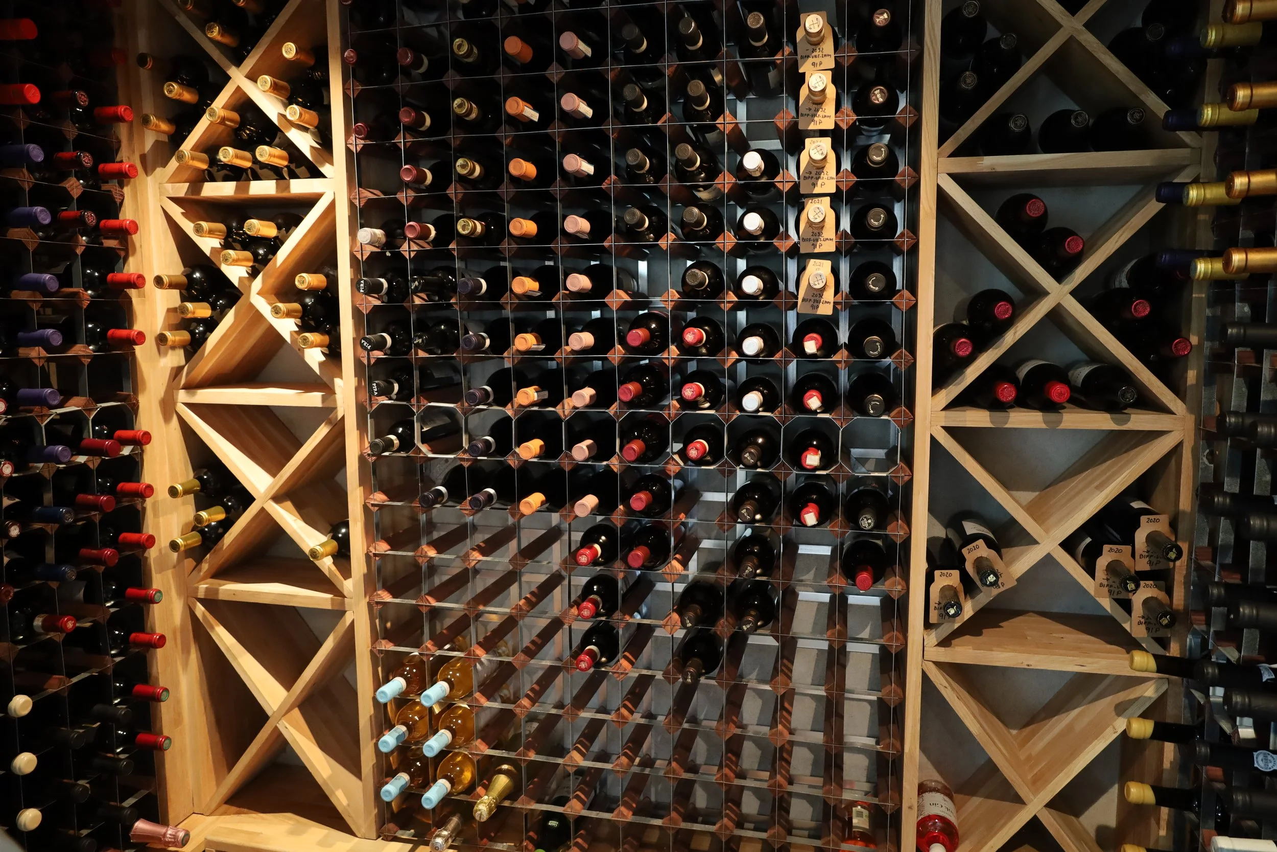 A wine rack filled with bottles arranged horizontally on wooden shelves, with diverse labels and colors.