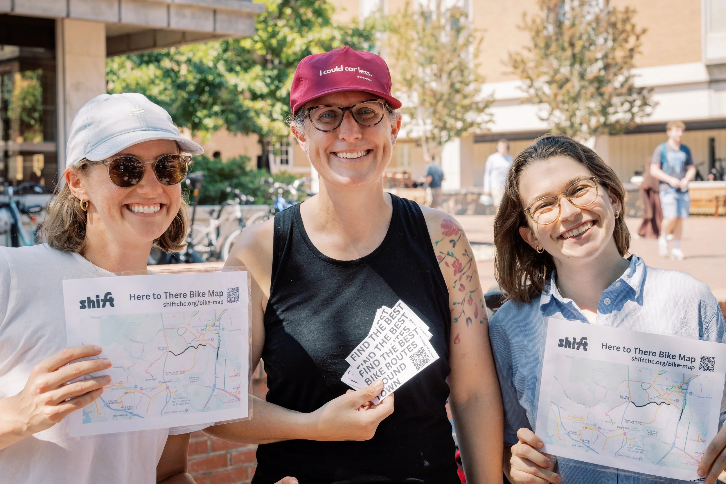 Two board members and a organization member with bike maps at an event