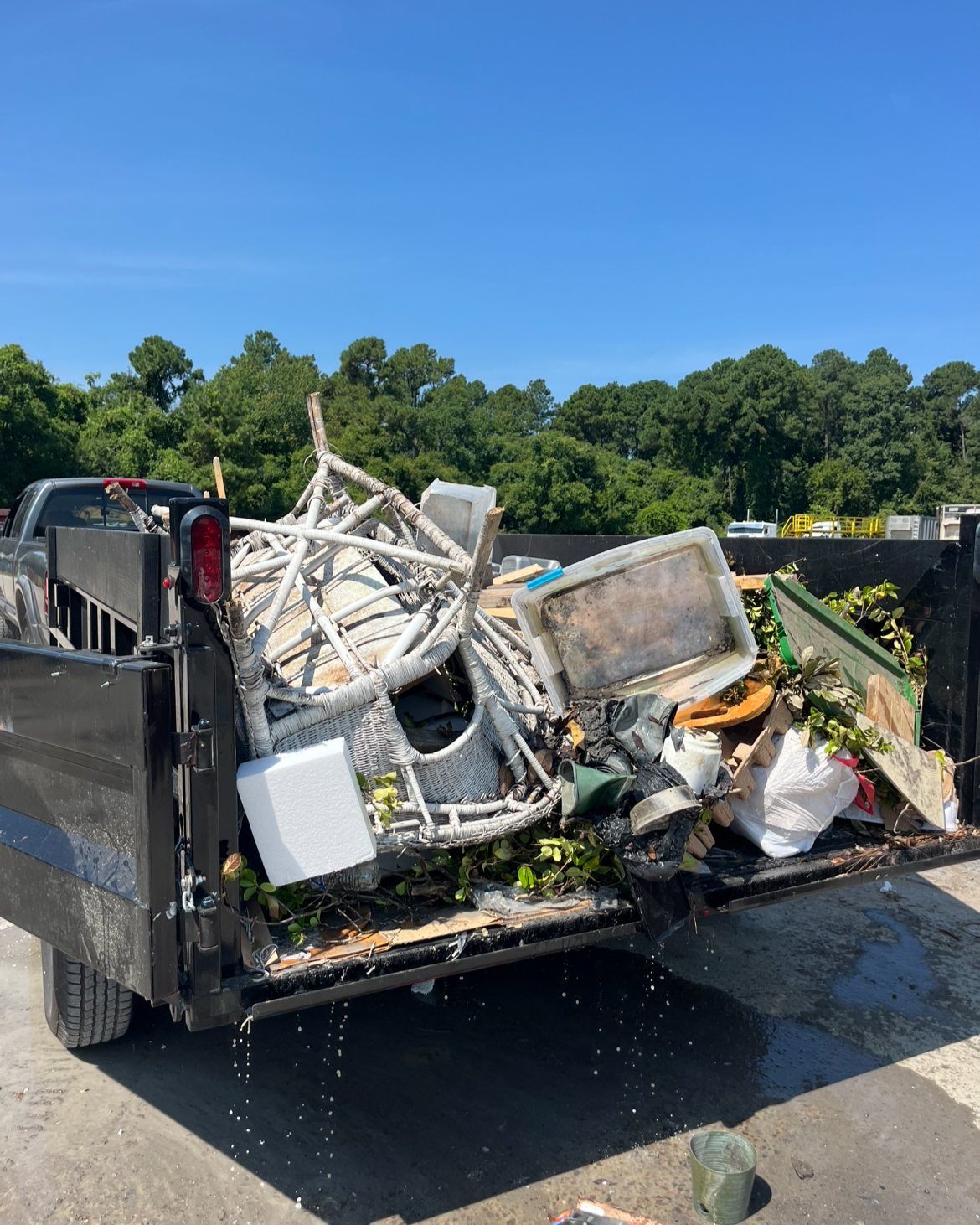 A black and white photo of a dump trailer in a scrapyard, with its bed raised.