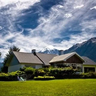 Hosteria rodeada de vegetación, con montañas y el lanin de fondo.