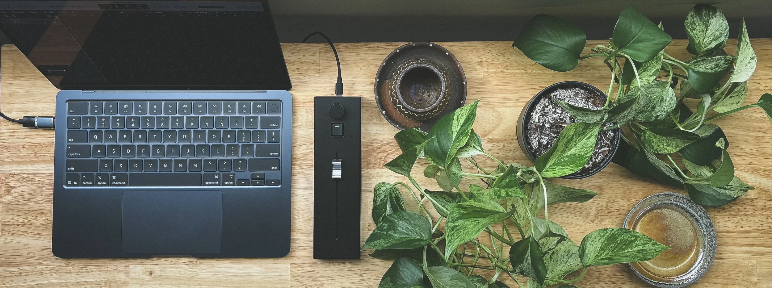 FADE on table next to laptop and plant, showcasing it's small footprint