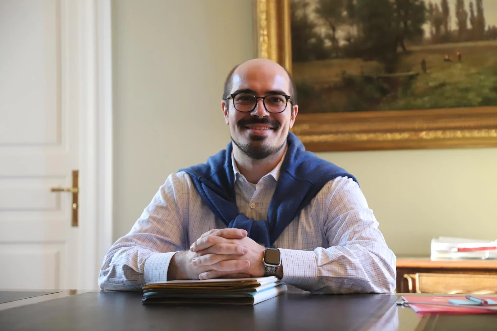 Attorney Matthew Waldron sitting at desk with arms folded on top of folders
