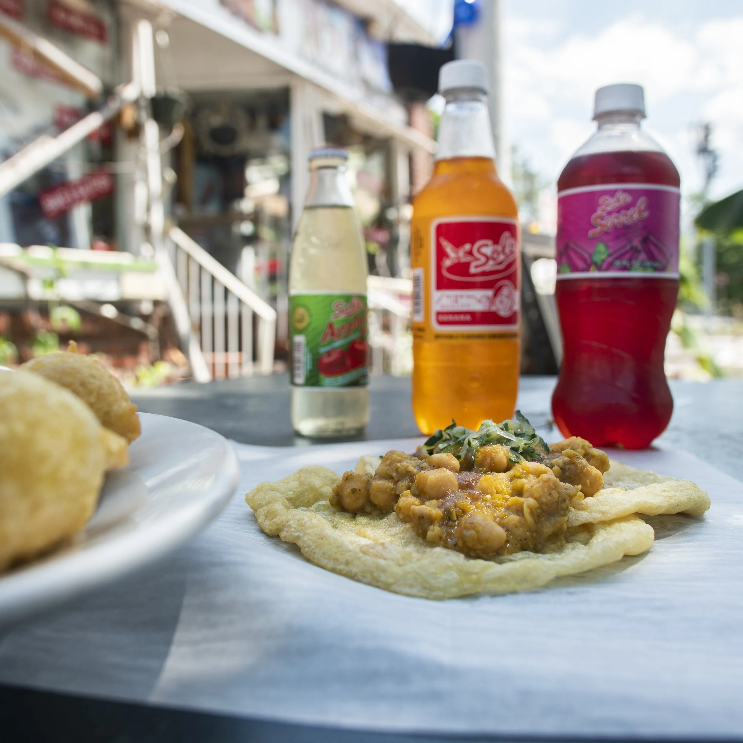 Cold bottles of soda and a plate with food on a table outdoors