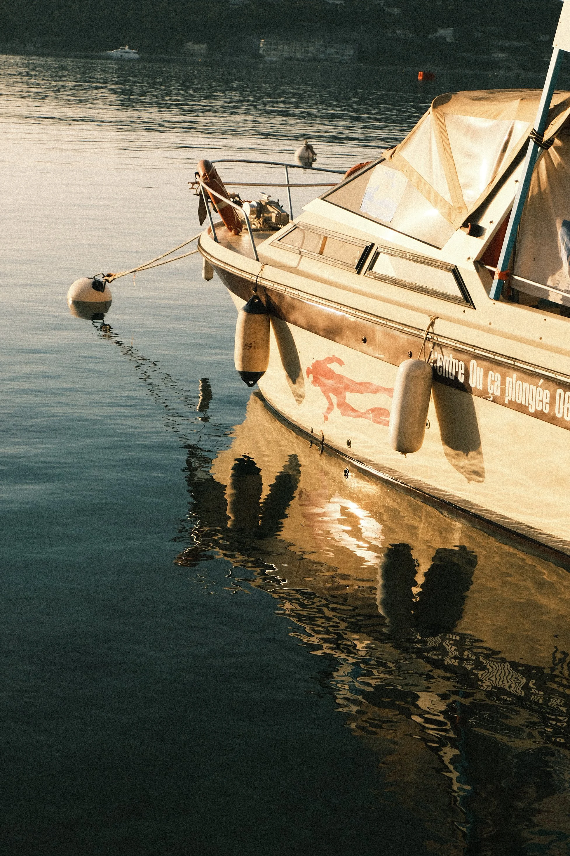 Bateau à moteur amarré dans l'eau avec une partie de son reflet visible sur la surface de l'eau, au crépuscule ou à l'aube.