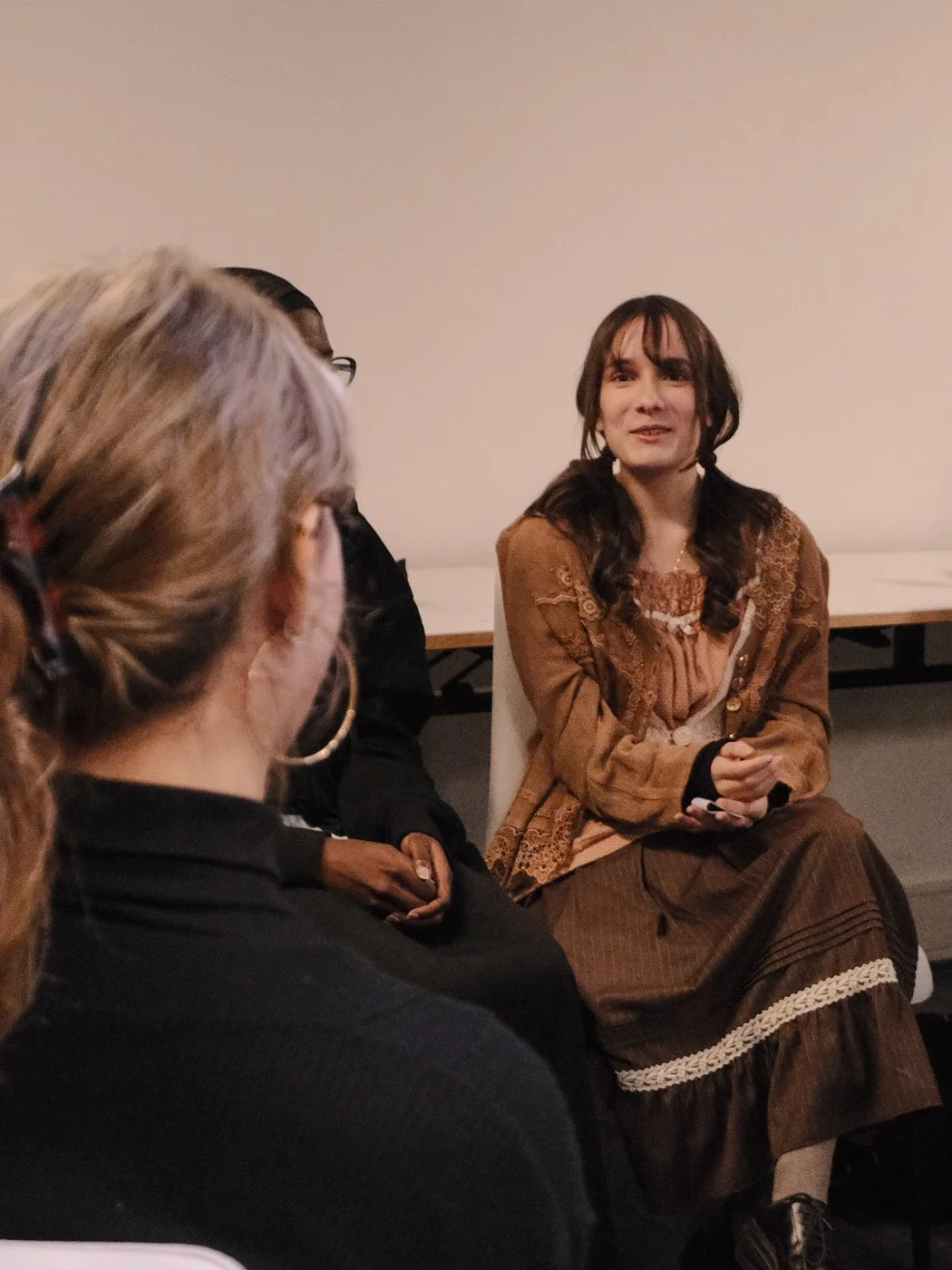Groupe de personnes en discussion lors d'une réunion ou d'un atelier, assises autour d'une table dans une pièce intérieure