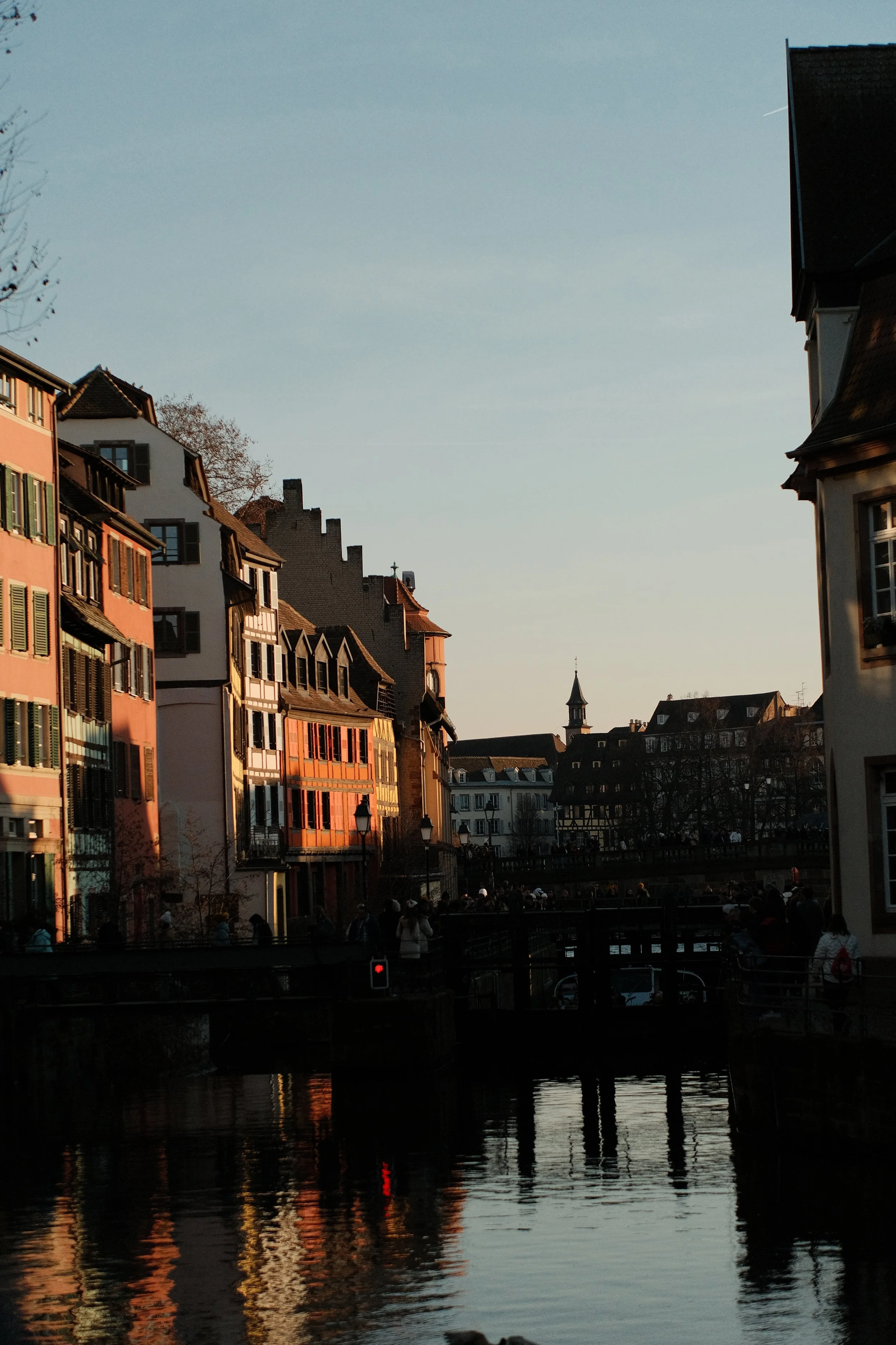 Vue d'une ville avec des bâtiments colorés le long d'une rivière, au coucher du soleil.