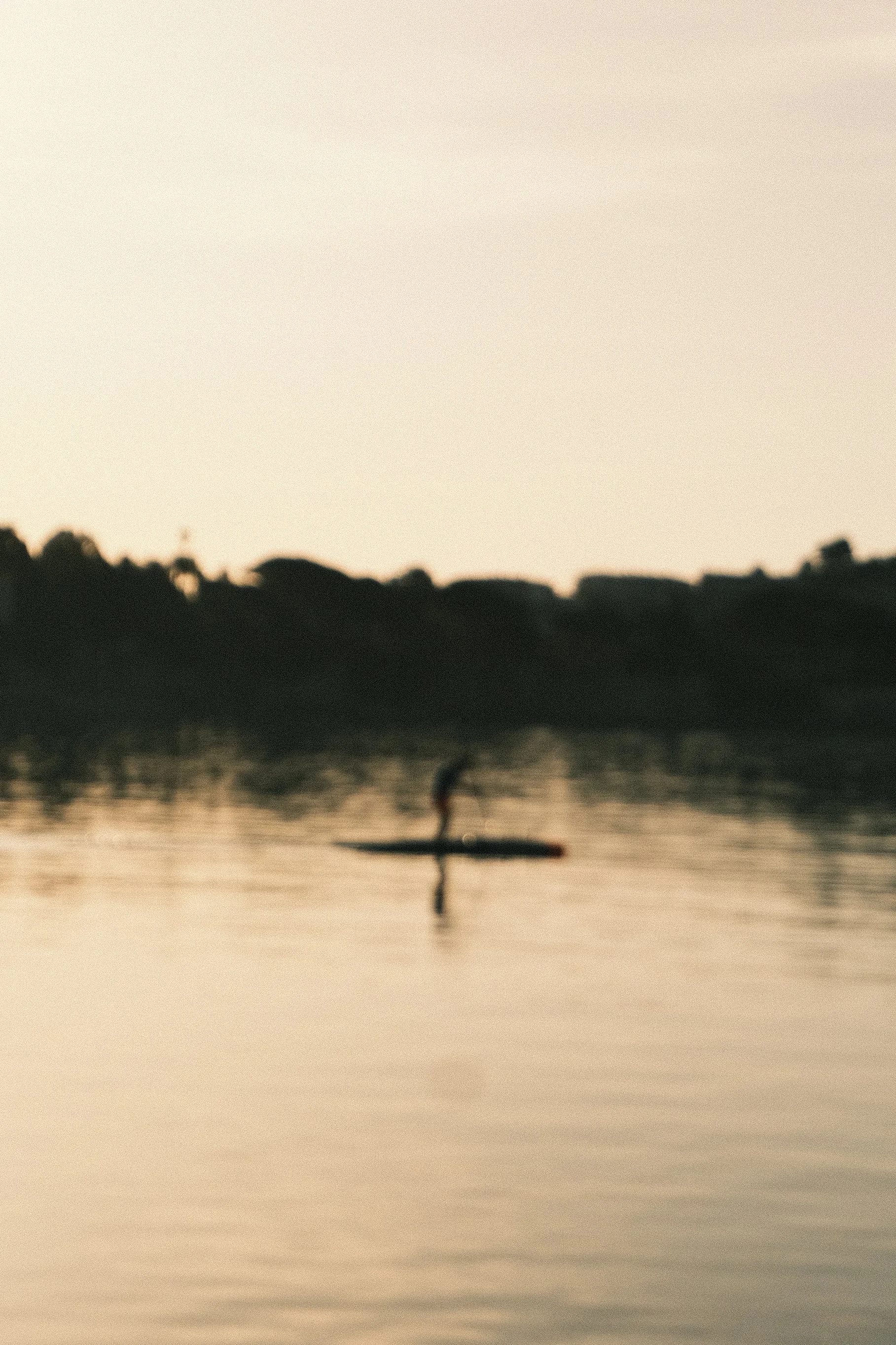 Une personne faites du paddle sur un lac au coucher de soleil.