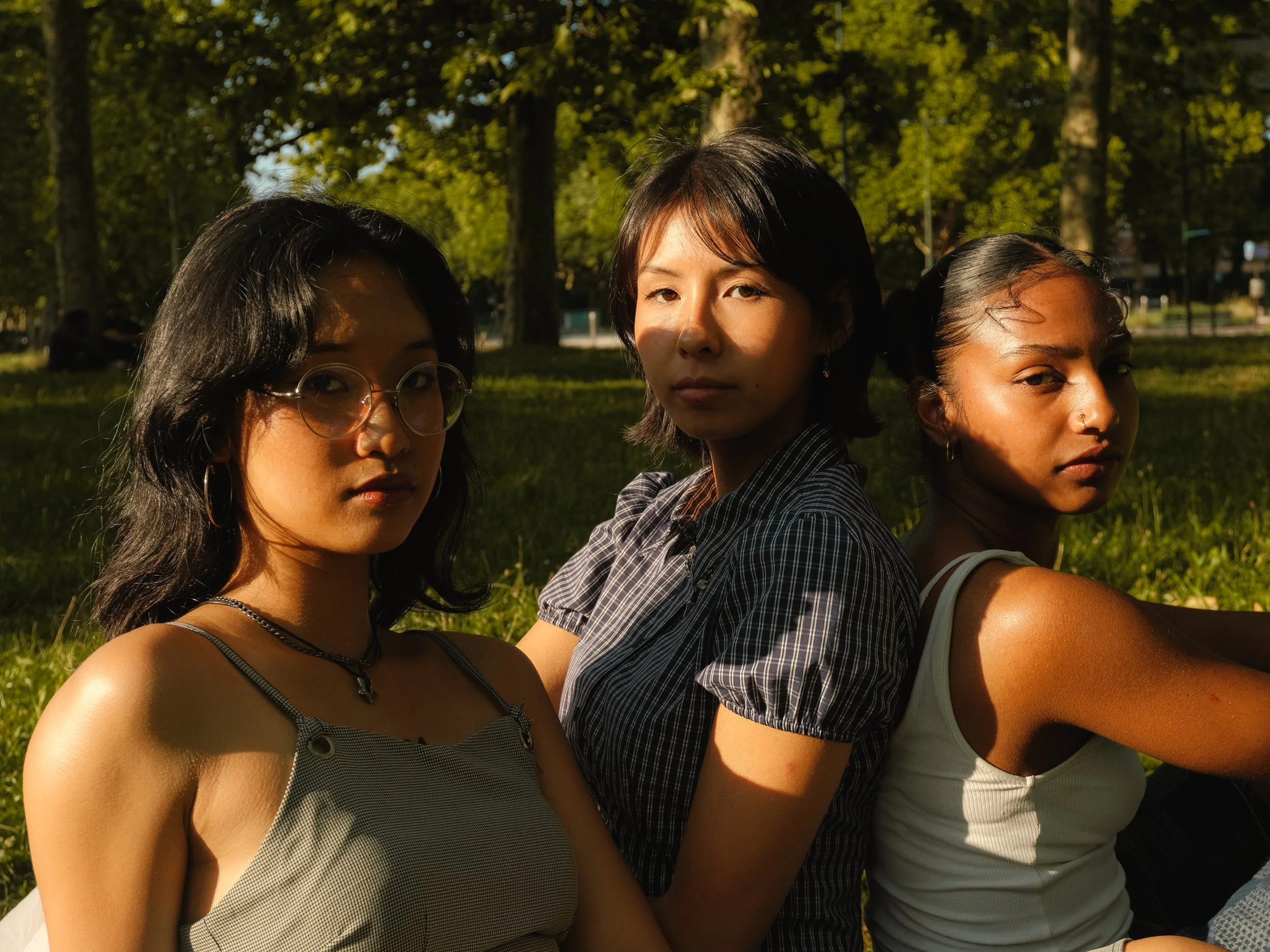 Trois jeunes femmes assises dans un parc, en plein après-midi. 