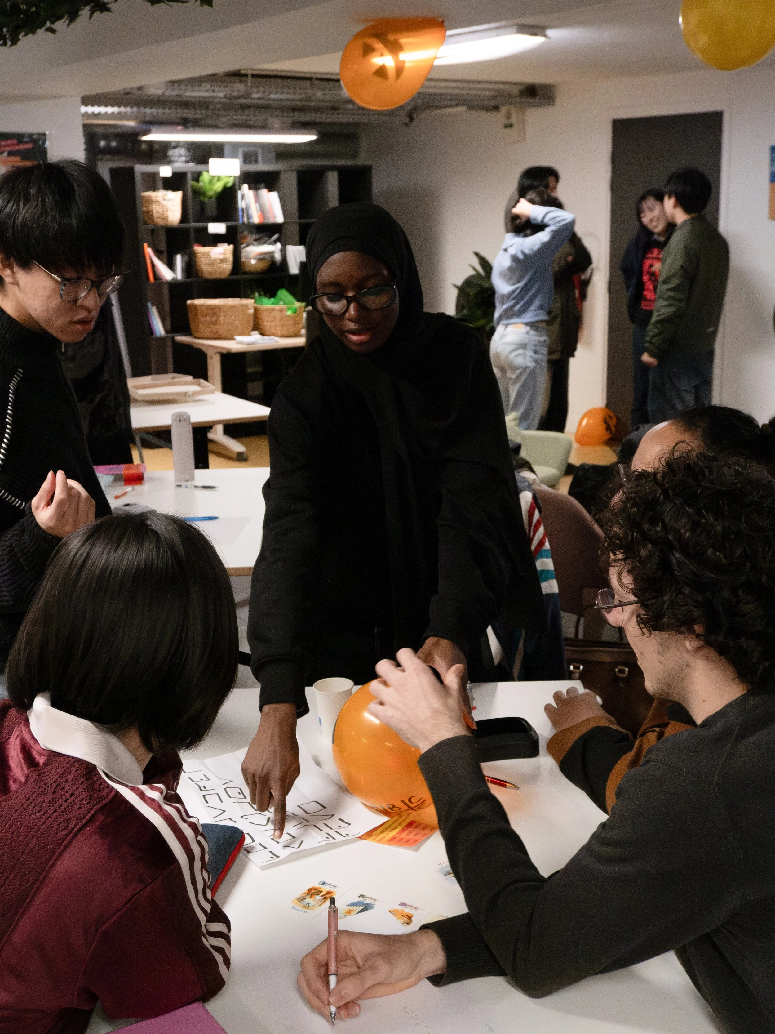 Groupe de personnes discutant autour d'une table, décorations d'Halloween comme des citrouilles et ballons