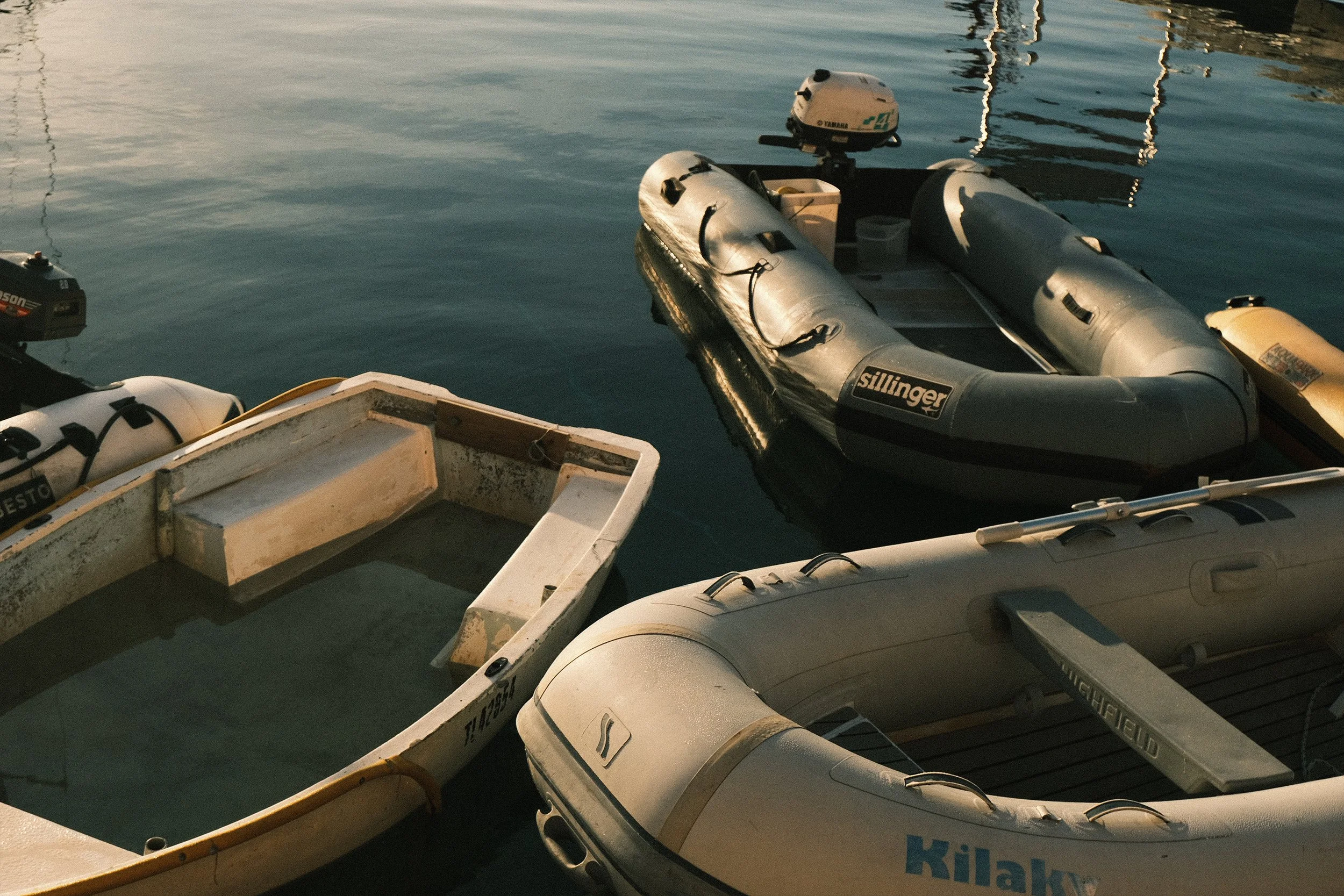 Plusieurs bateaux pneumatiques amarrés dans l'eau, certains semblent désuets ou abandonnés.