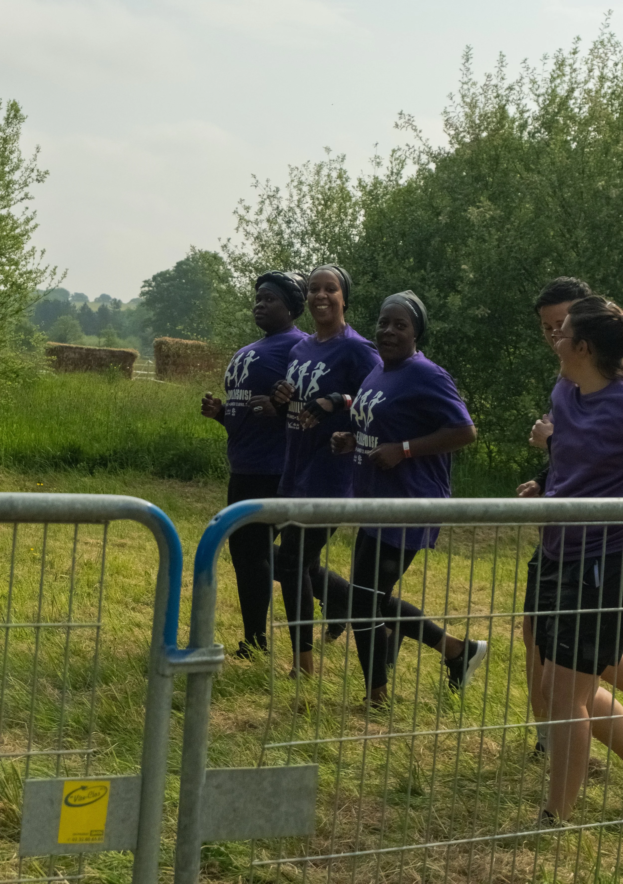 Groupe de femmes courant dans un champ en plein air, portant des T-shirts violets.