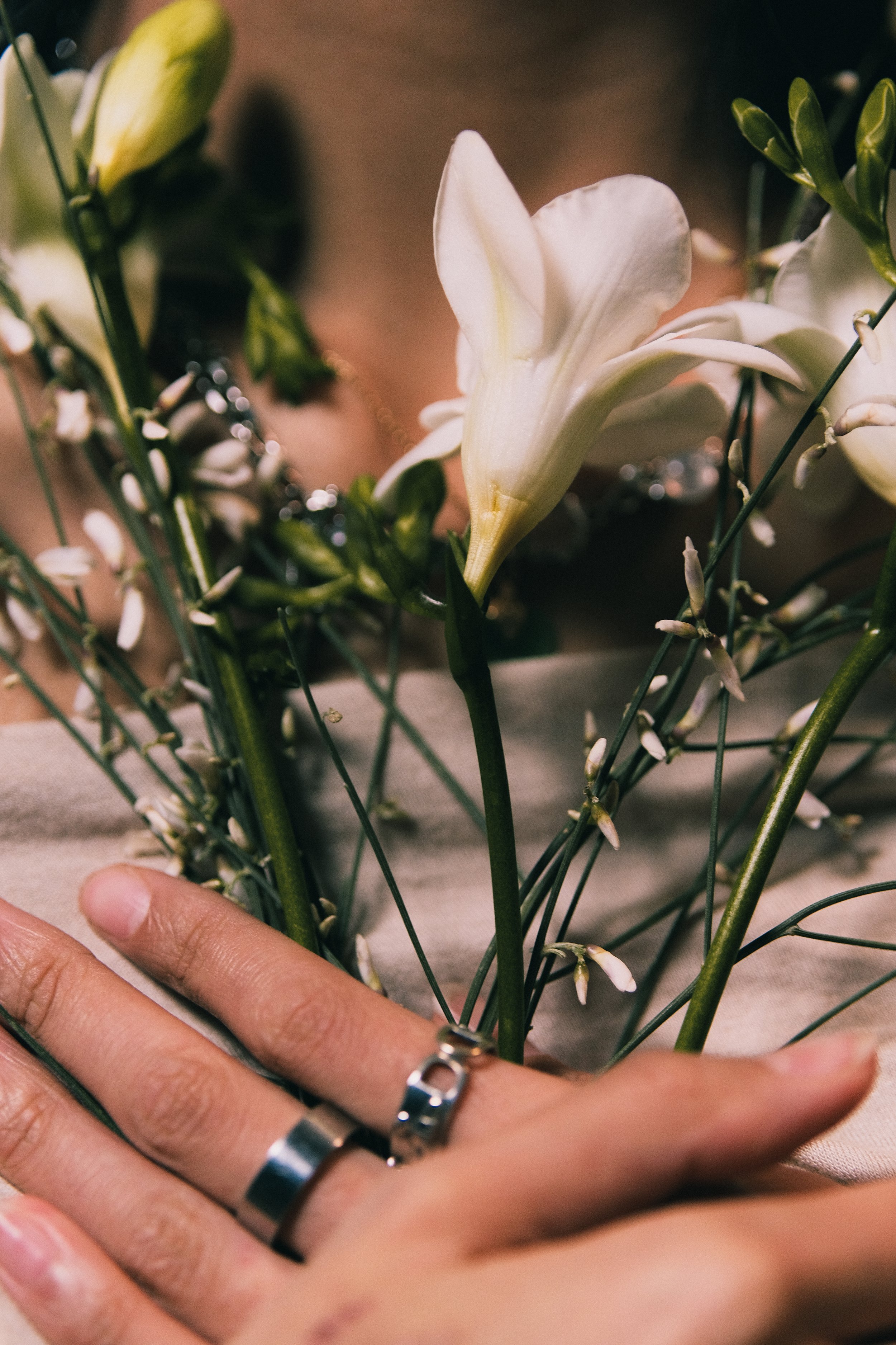 Main proche d'une main tenant un bouquet de fleurs blanches, incluant un lily blanc