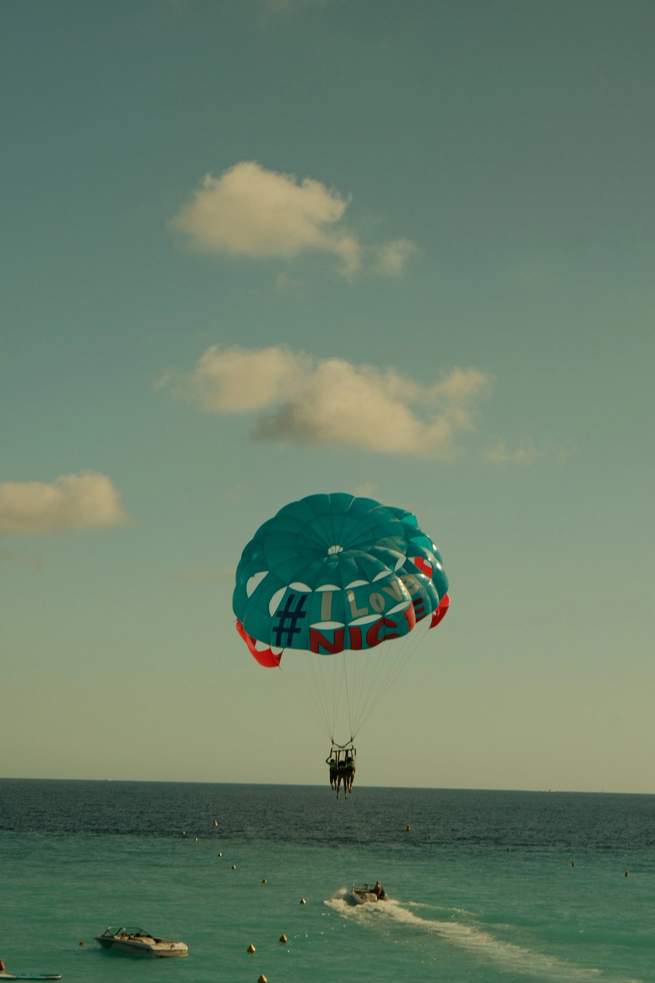 Parachute avec le hashtag #I Love NICE, survolant la mer avec des bateaux en dessous.