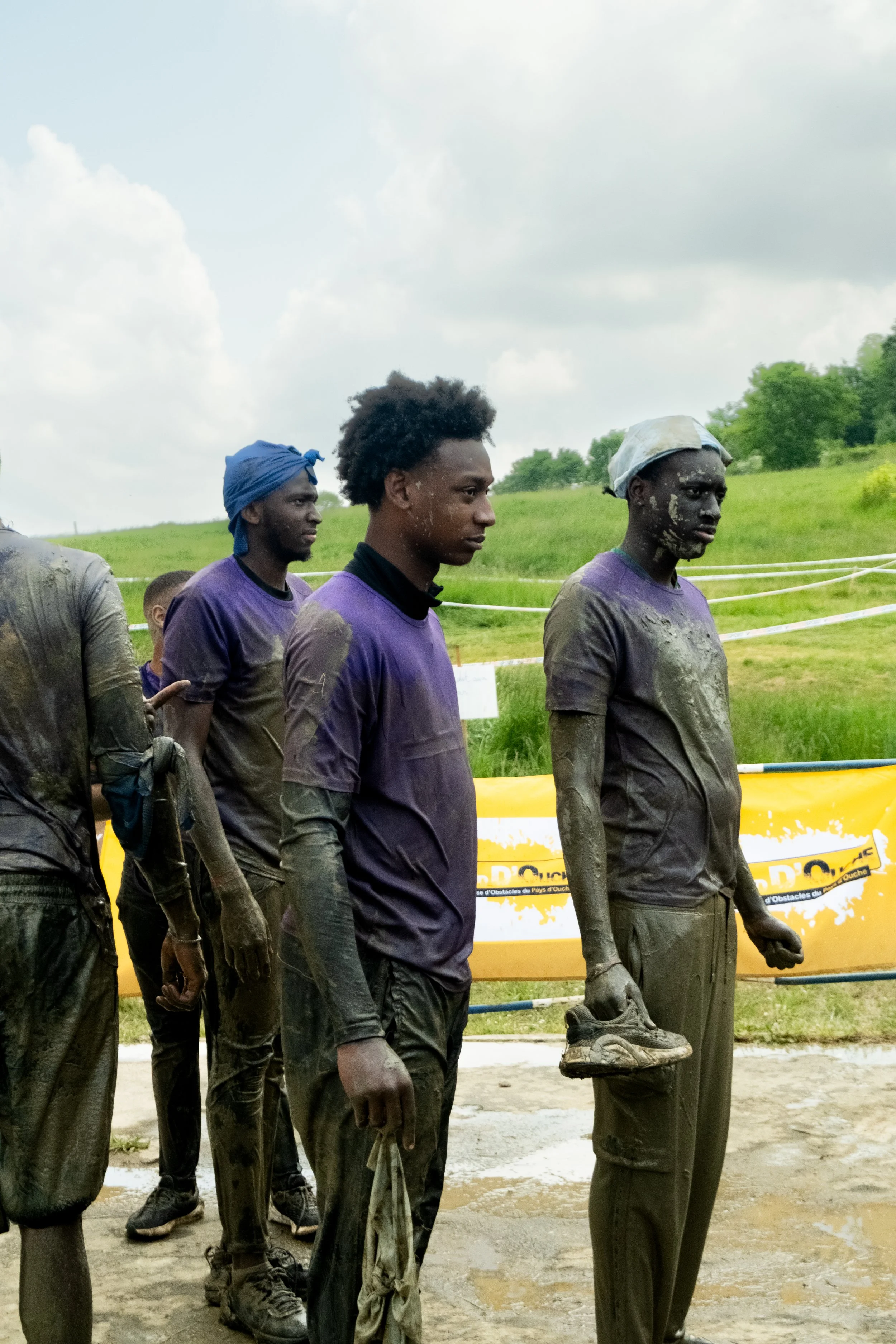 Groupe de jeunes athlètes, coureurs, couverts de boue lors d'une compétition en plein air.