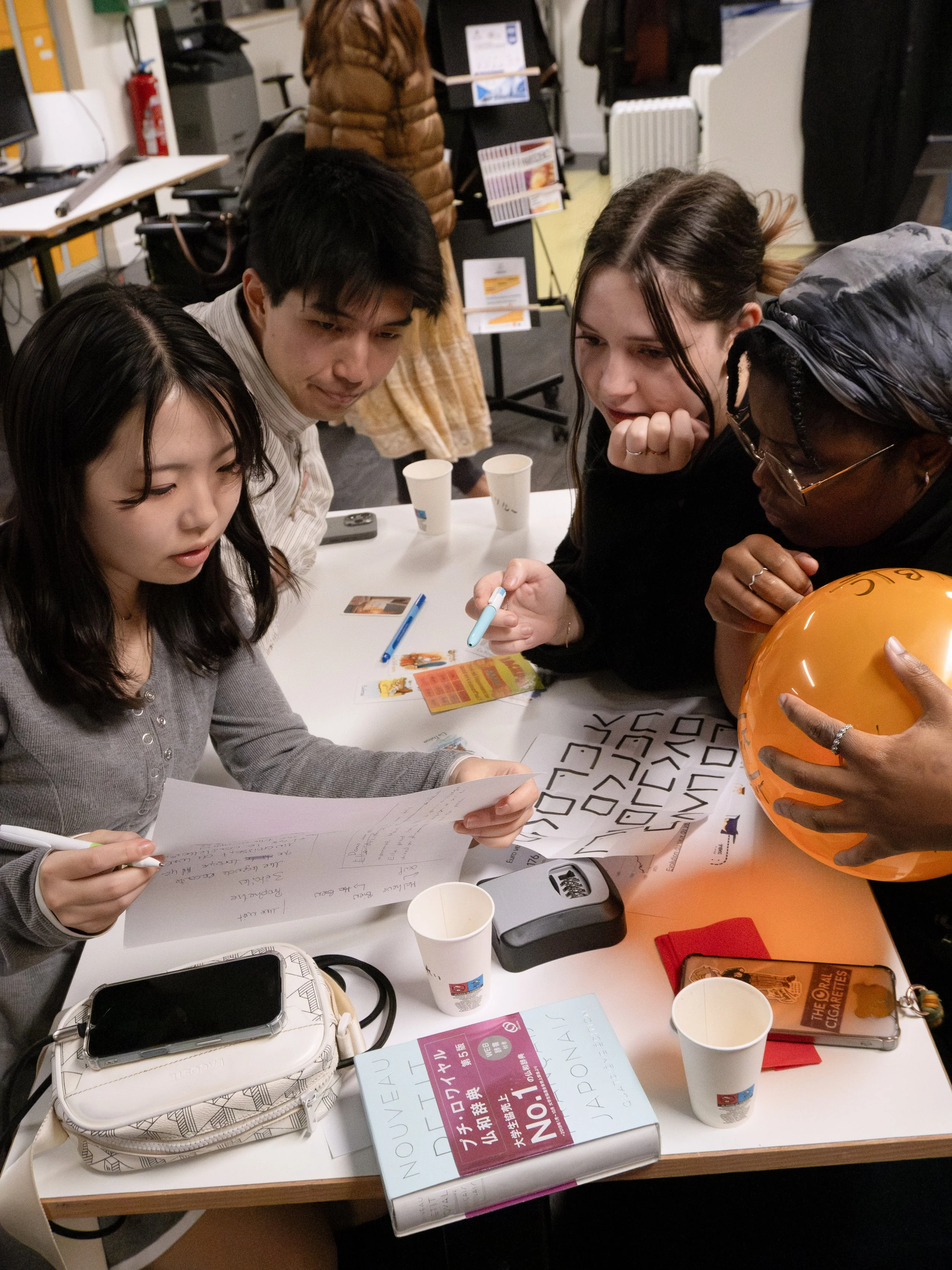 Groupe de personnes autour d'une table, discutant et partageant des idées lors d'une activité ou réunion.