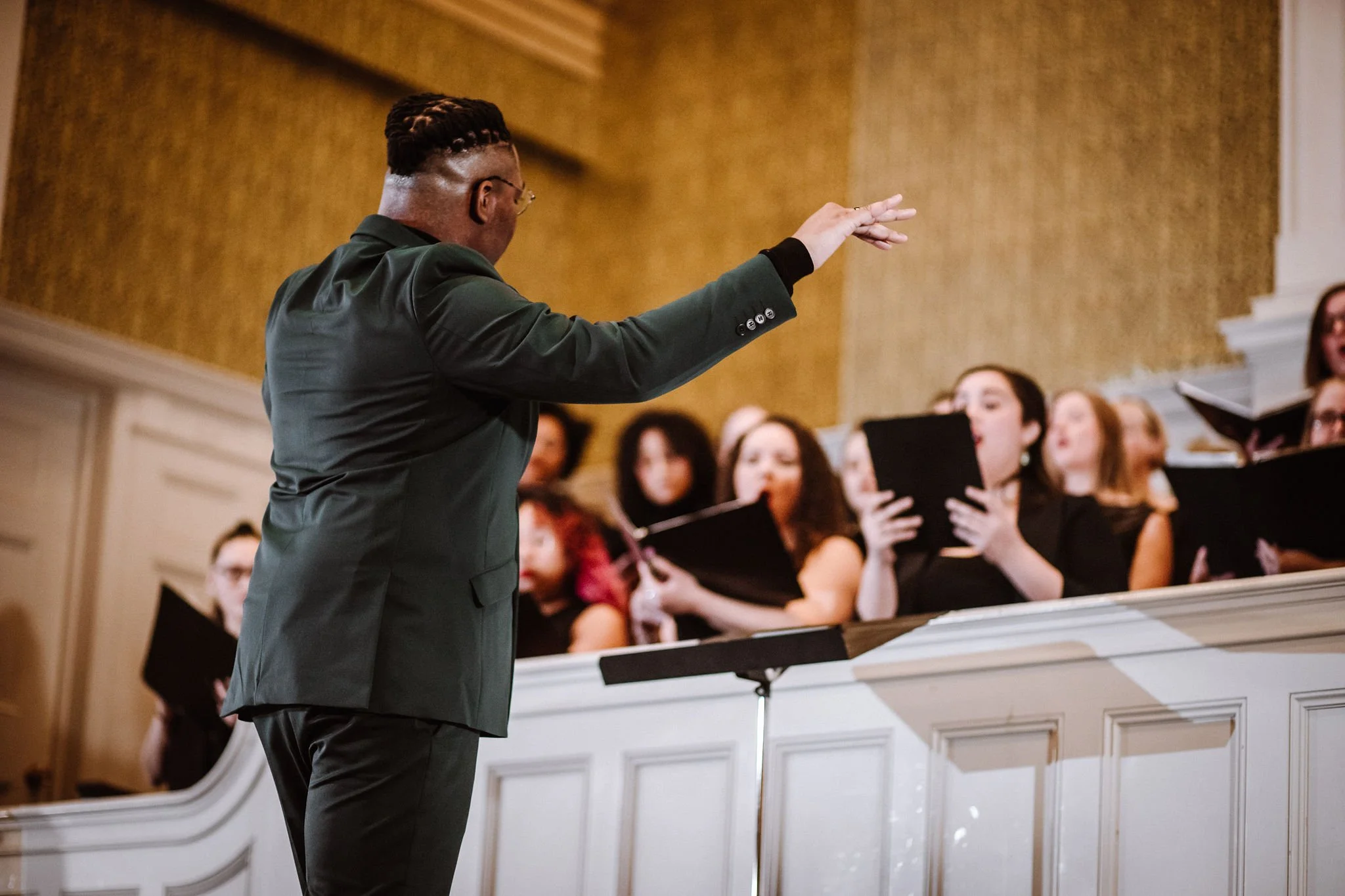 Conductor leading a choir during a performance in a concert hall.