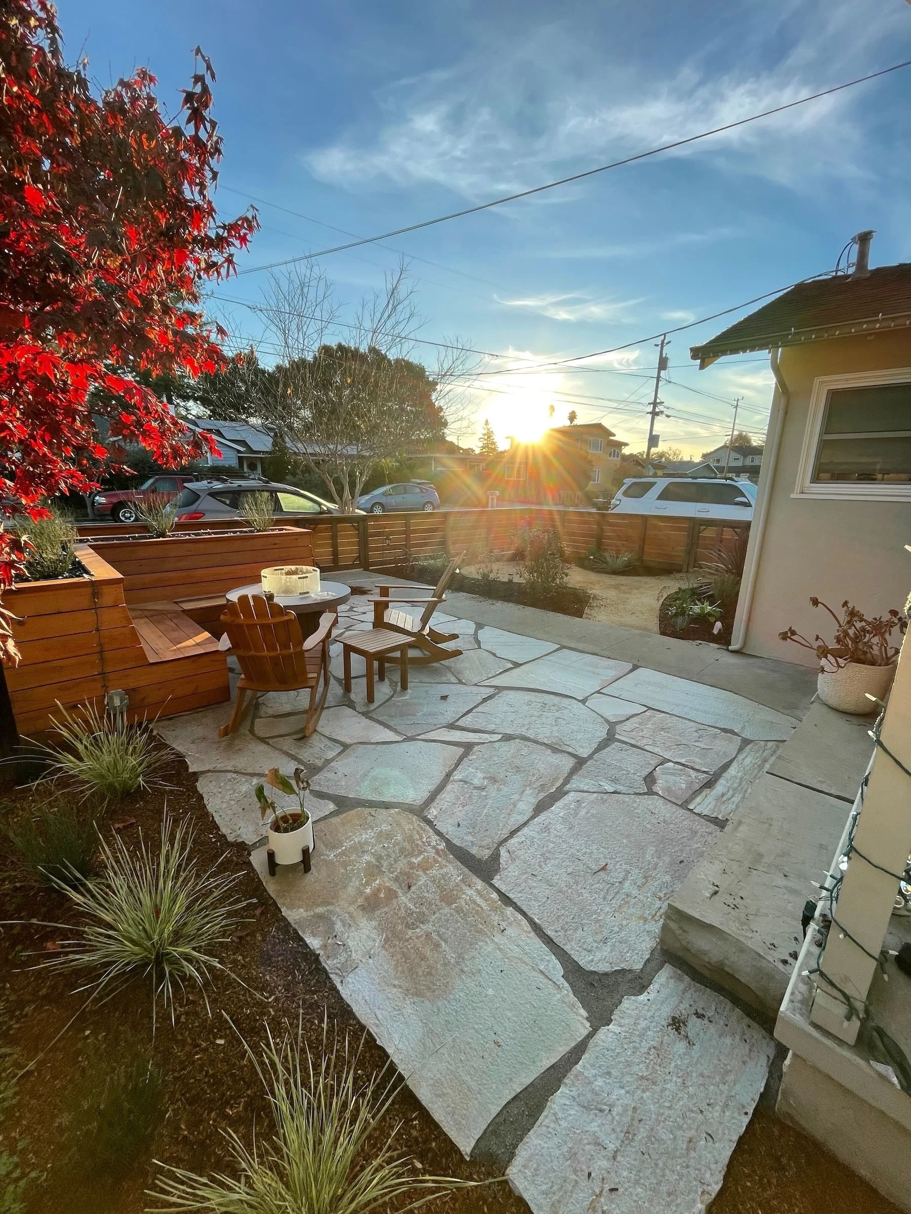 Finished flagstone patio with outdoor seating and wood fencing at sunset - Orchard Keepers