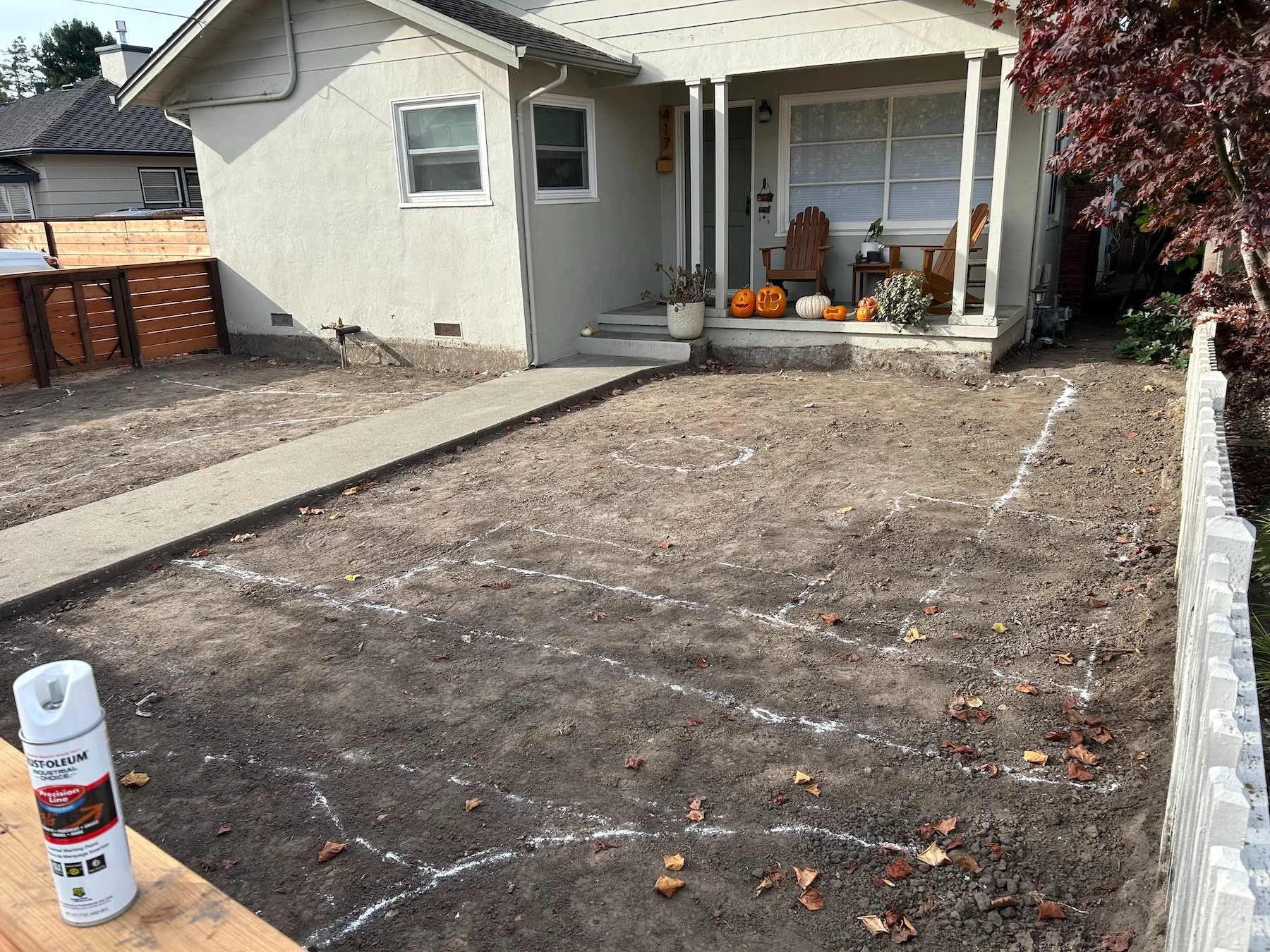 Front yard bare dirt with white spray-paint outlines marking a new landscape design layout