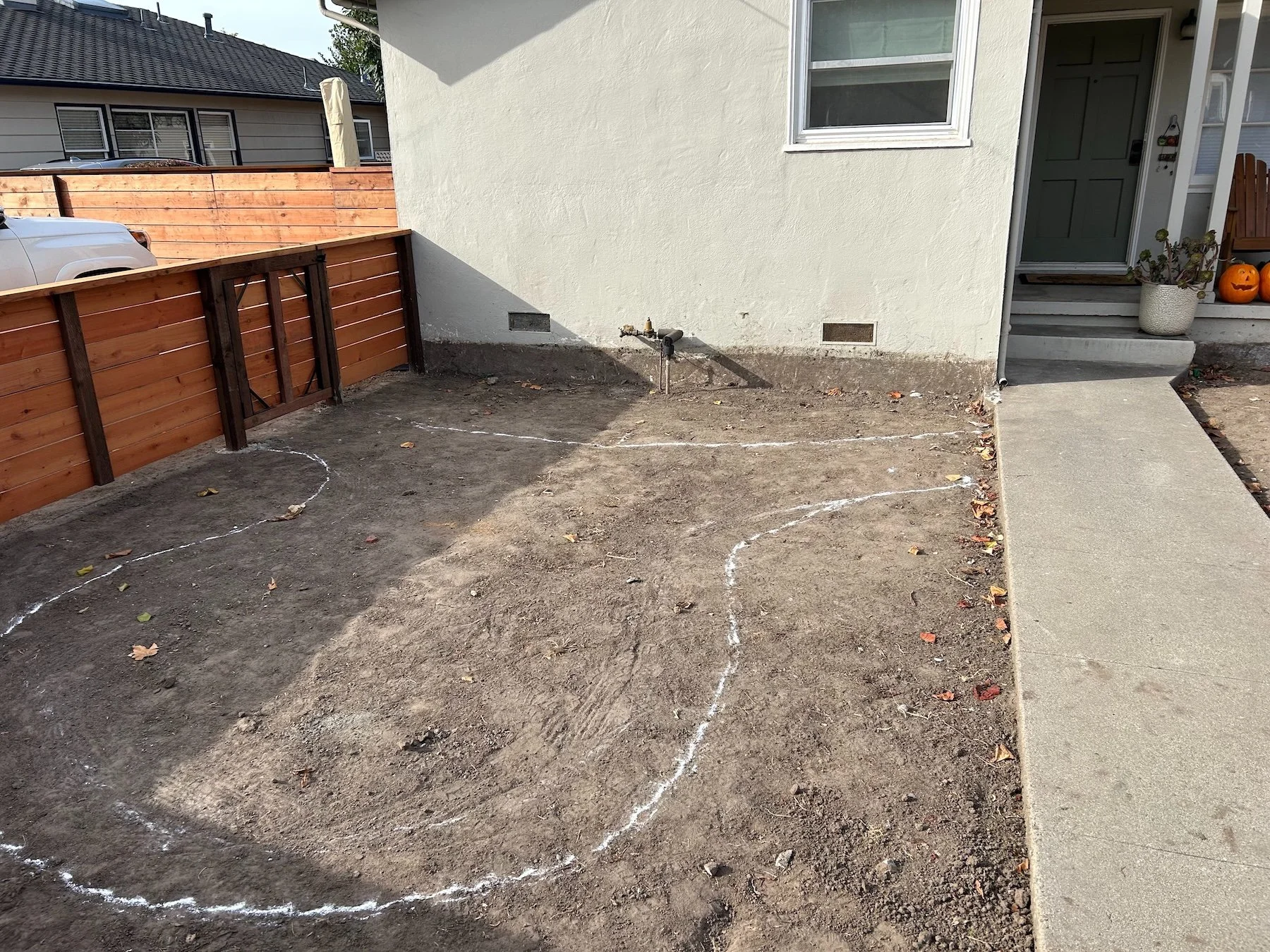 Side yard with new cedar wood fence and spray-painted layout lines for a landscape renovation