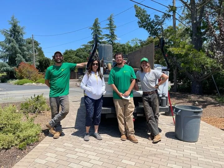 Four crew members gathered in front of a work truck on a paver driveway — Orchard Keepers