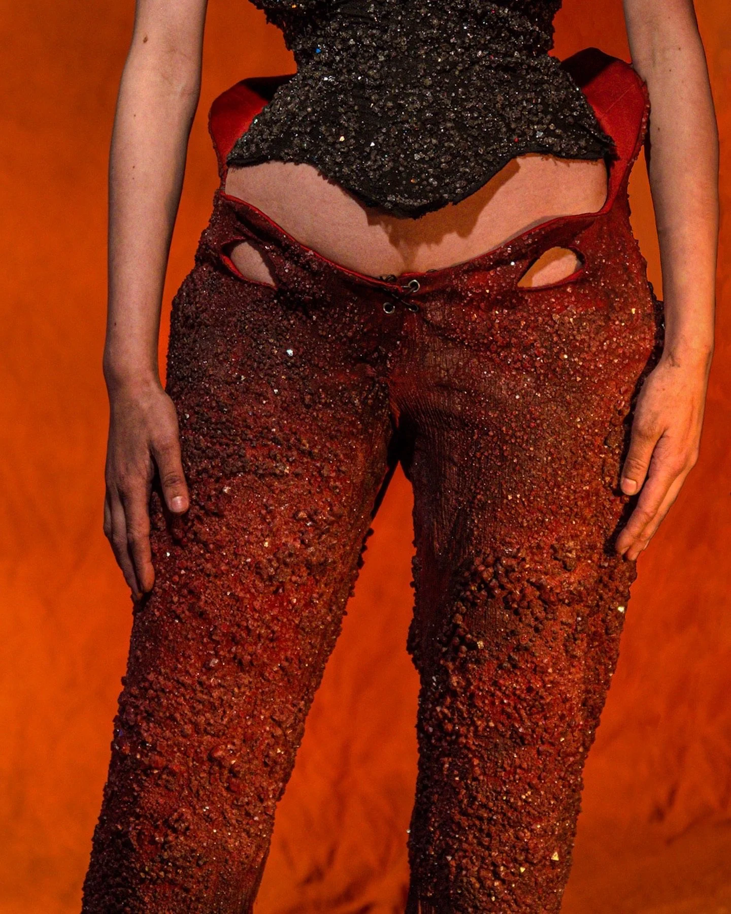 A person wearing red pants and a black top, with the focus on their lower torso and legs.