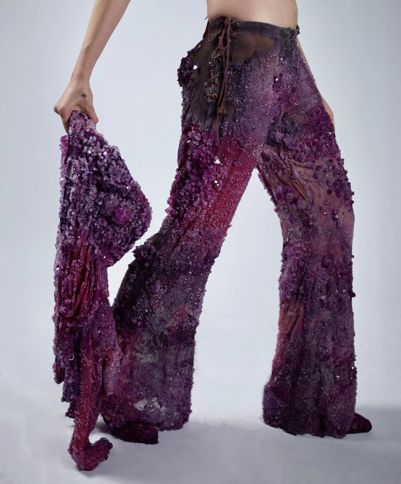 Person holding a piece of textured, colorful fabric with purple, pink, and black hues.