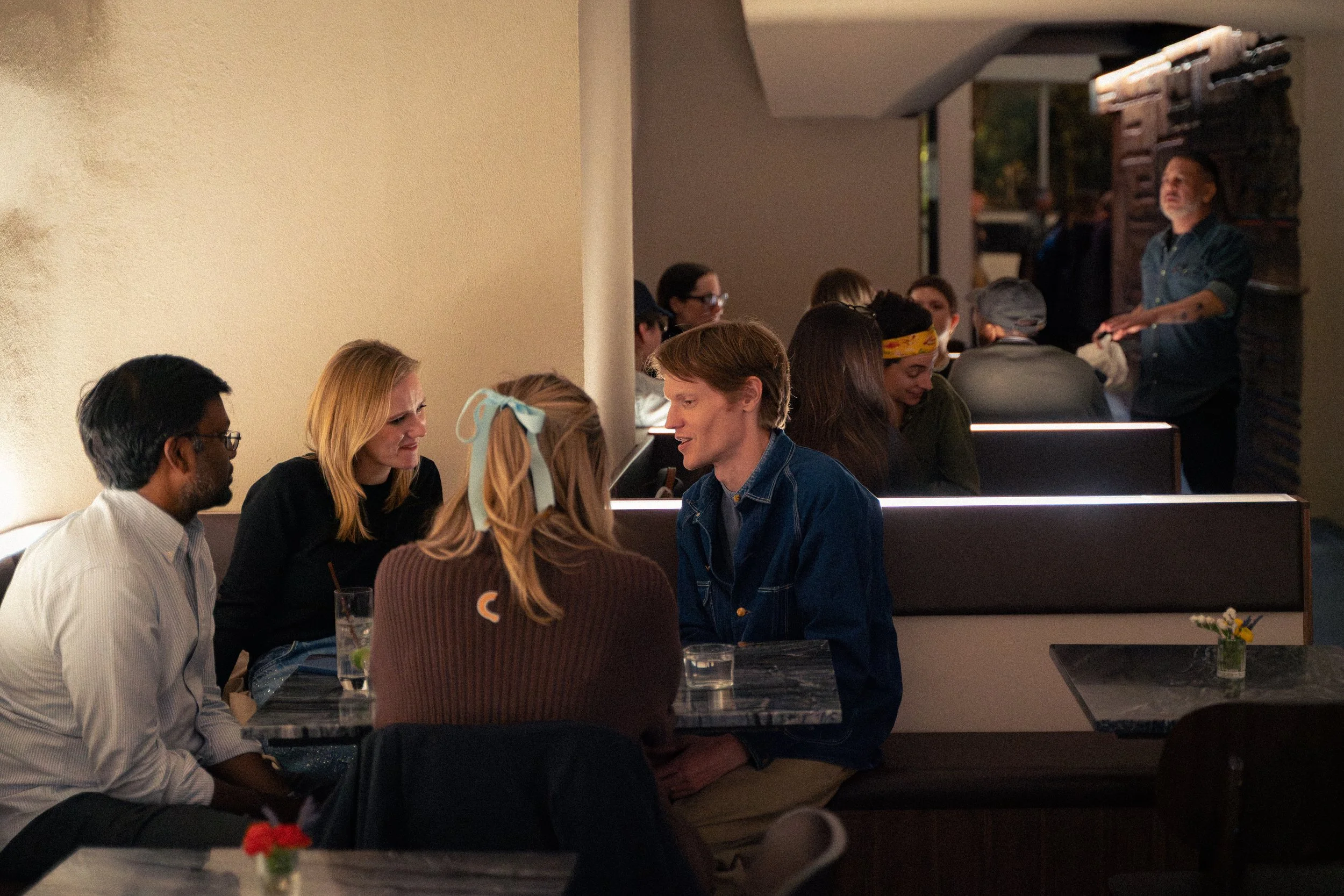 People sitting at tables and chatting inside a restaurant.