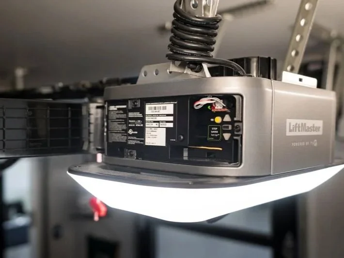 Close-up of a LiftMaster garage door opener with wiring and LED lights, mounted on the ceiling.