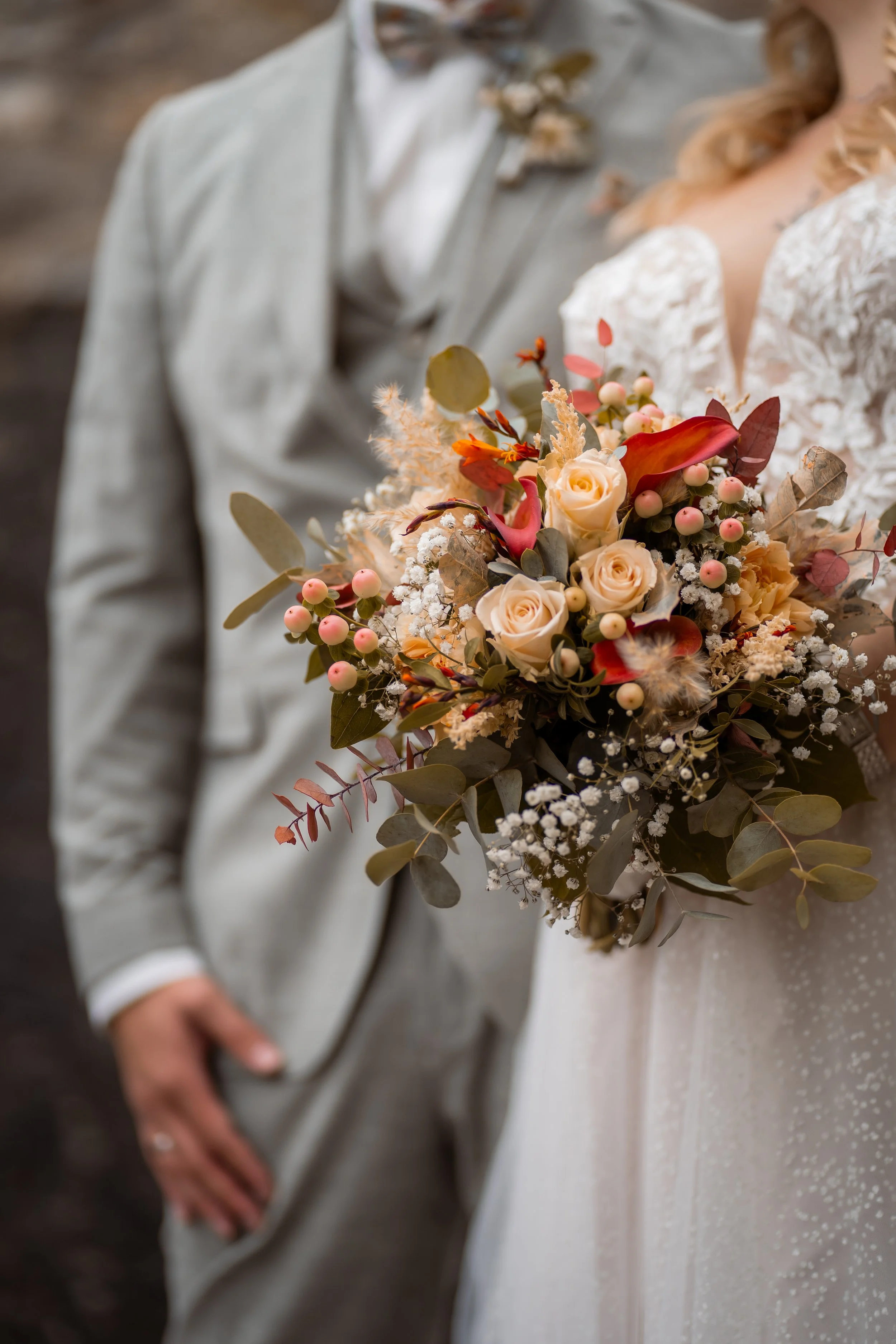 Ein Brautpaar bei einer Hochzeit, das eine Bouquet aus Blumen hält.