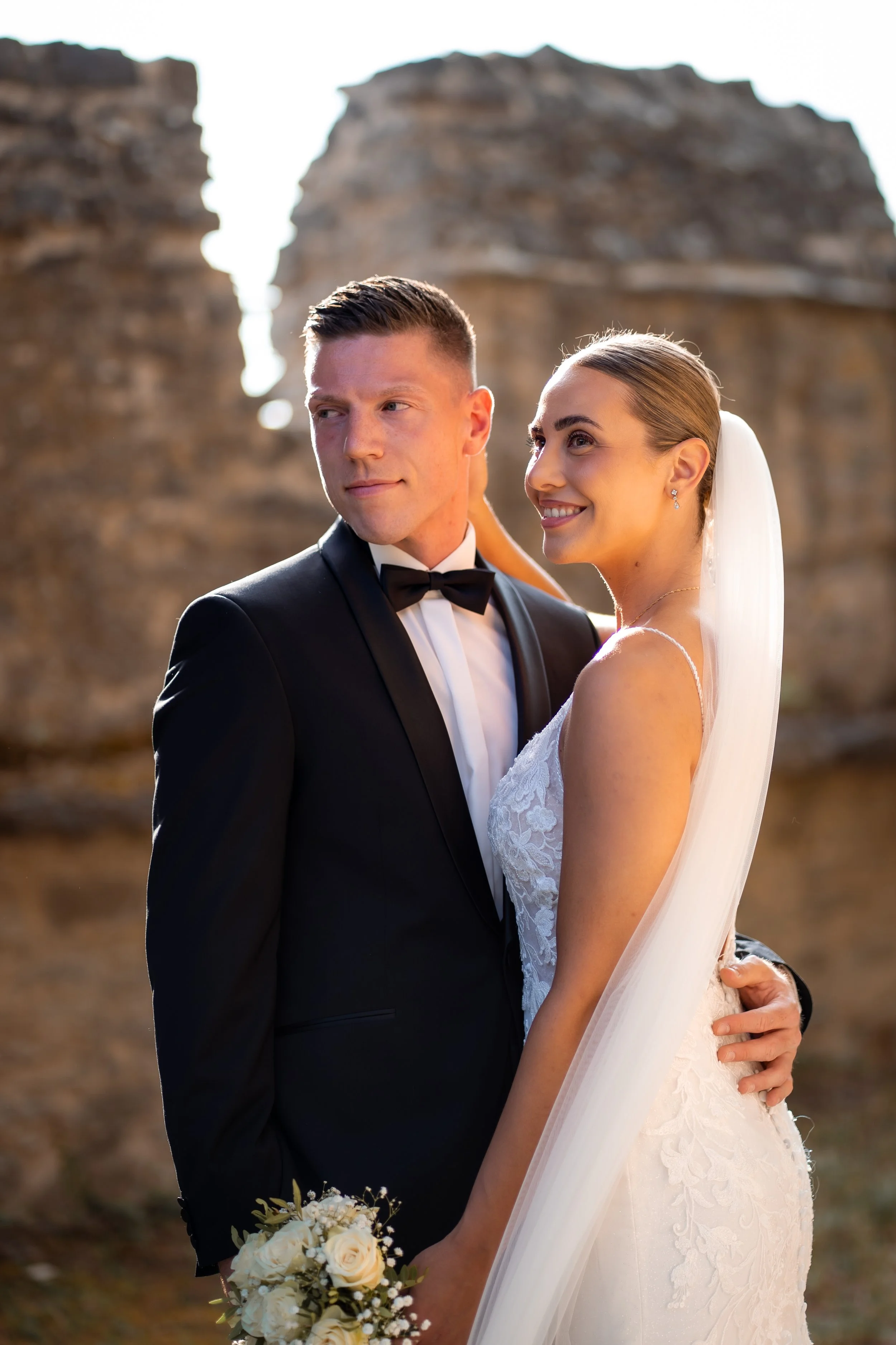 Braut und Bräutigam bei einer Hochzeit im Freien, die auf einer Lichtung mit Felsen im Hintergrund stehen.