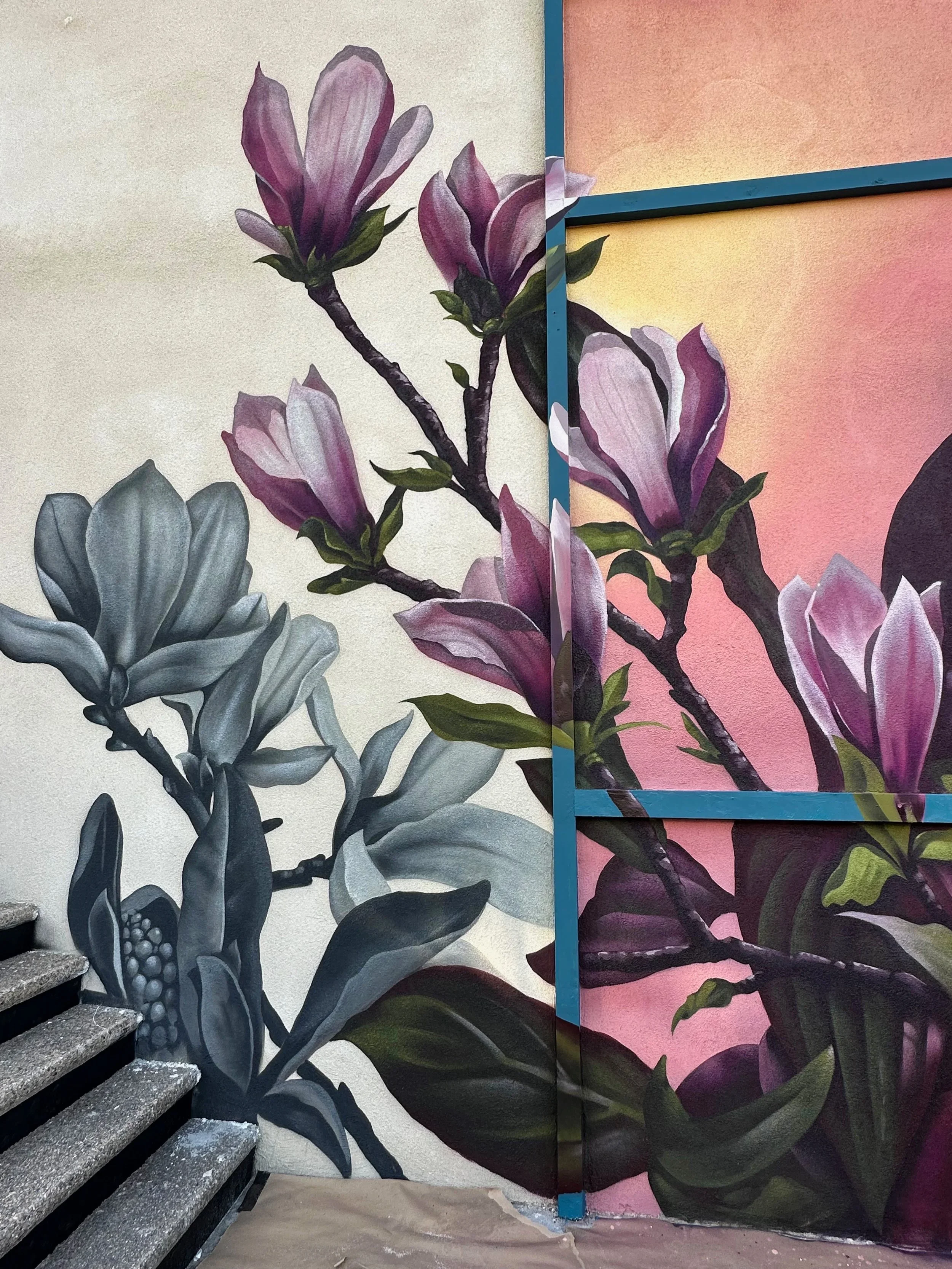 Wall mural of blooming magnolia flowers with large pink, purple, and gray petals against a background of different shades of pastel colors.