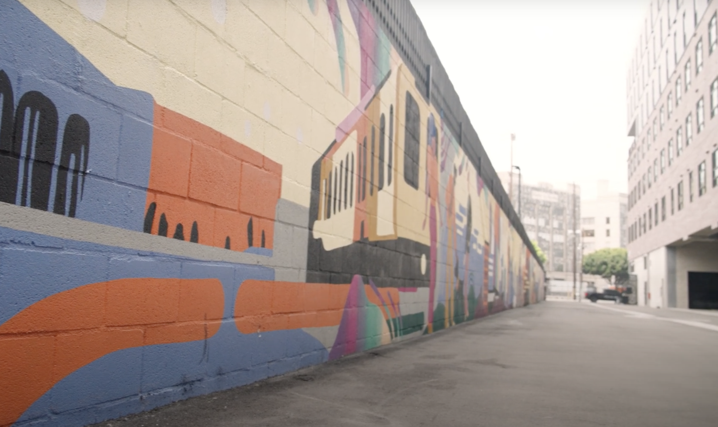 Close-up of a mural section showing “The Beverly Hills” sign surrounded by palm trees, figures celebrating, and colorful wave-like patterns symbolizing culture and community.
