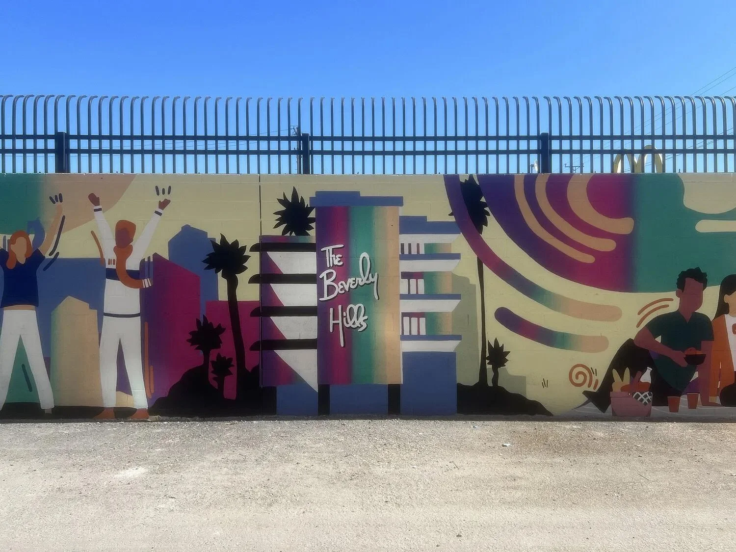 Wide view of the alley with the mural running the entire length of the block, depicting buses, trains, and architectural silhouettes, bringing color and energy into the urban corridor.