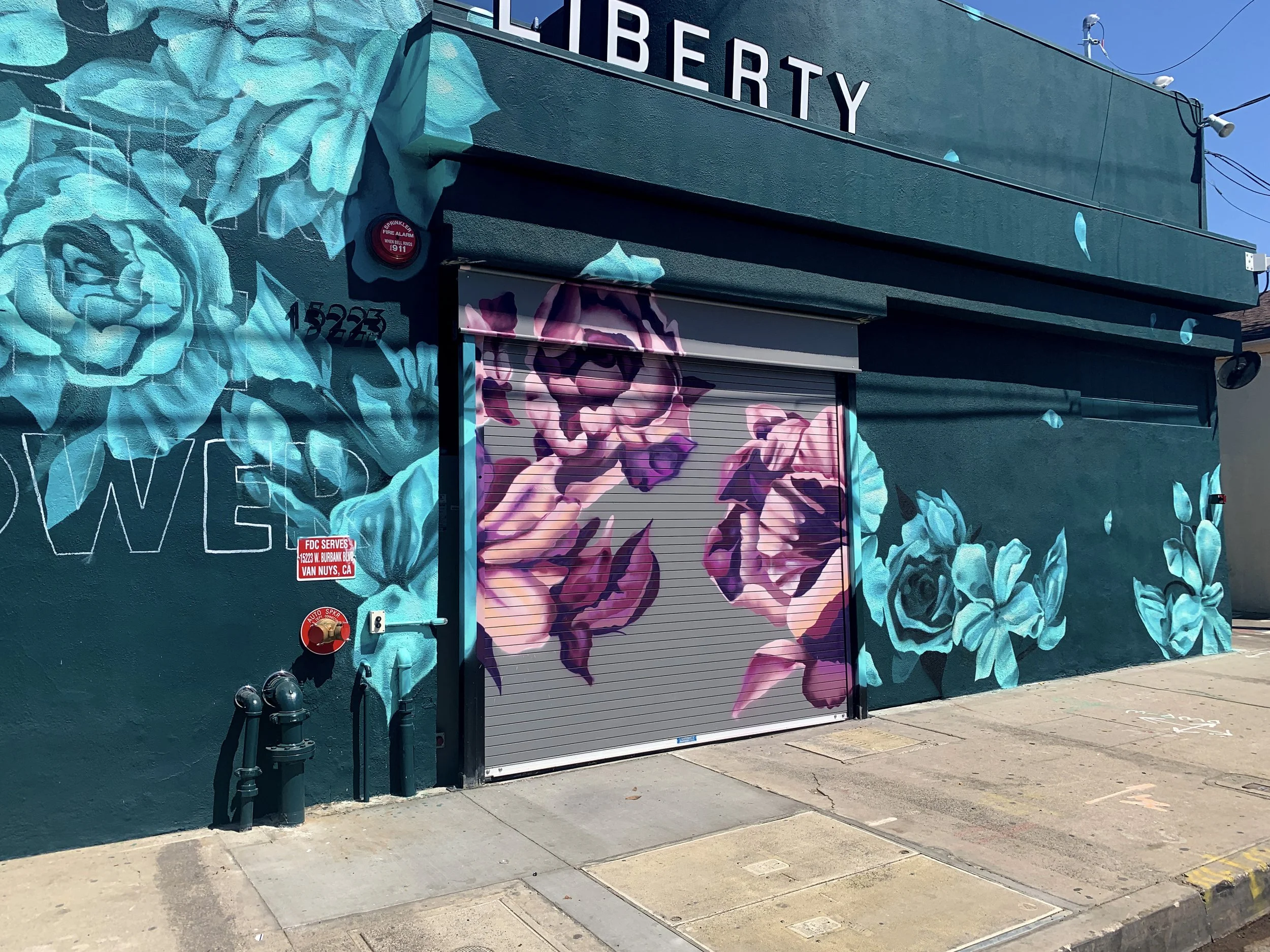 Retail space exterior mural in Los Angeles for Liberty Cannabis combining large scale floral artwork and branded storefront design by Yanoe.