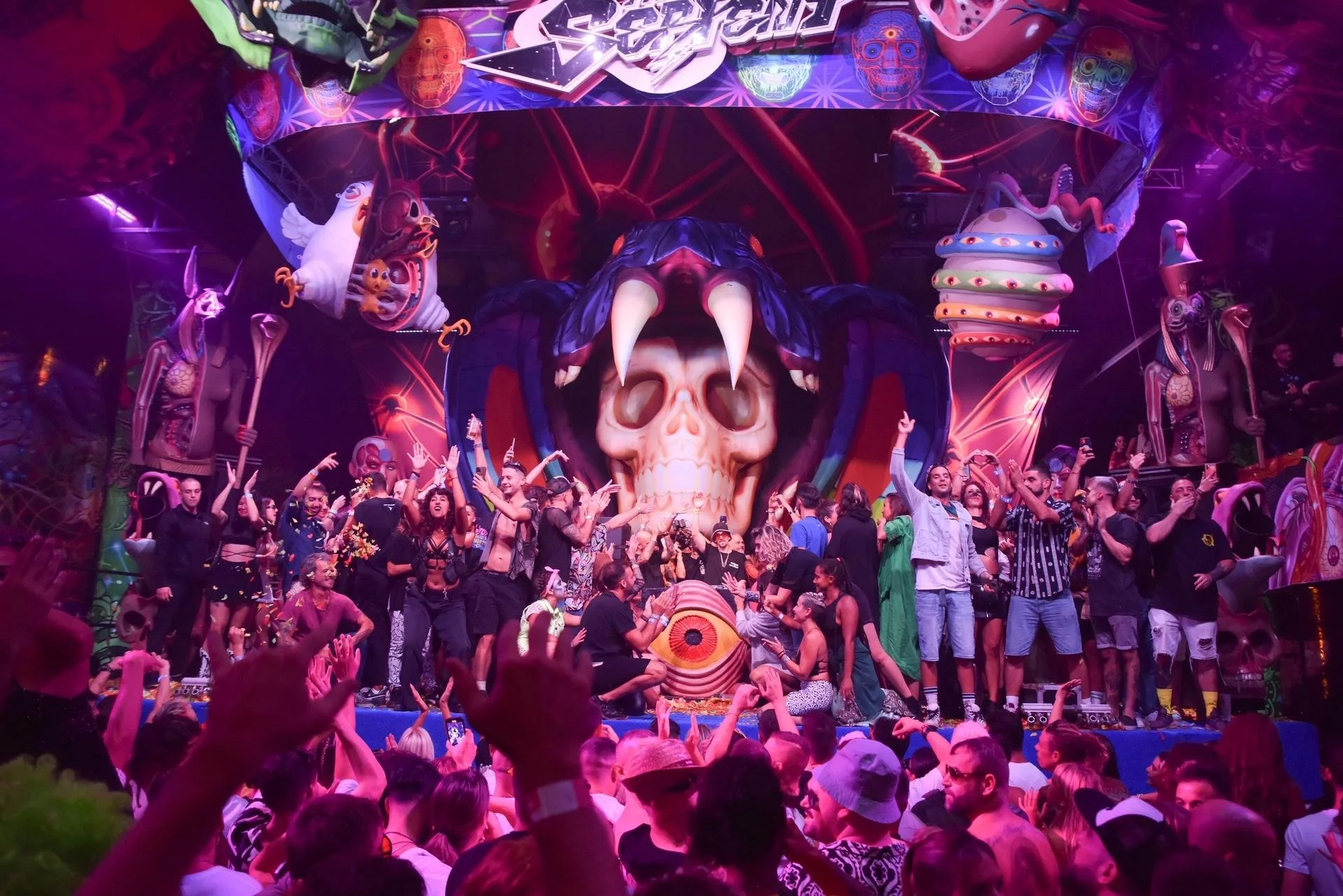 Daylight view of the serpent-and-skull stage build showing inflatable elements, rigging, and printed scenic banners.