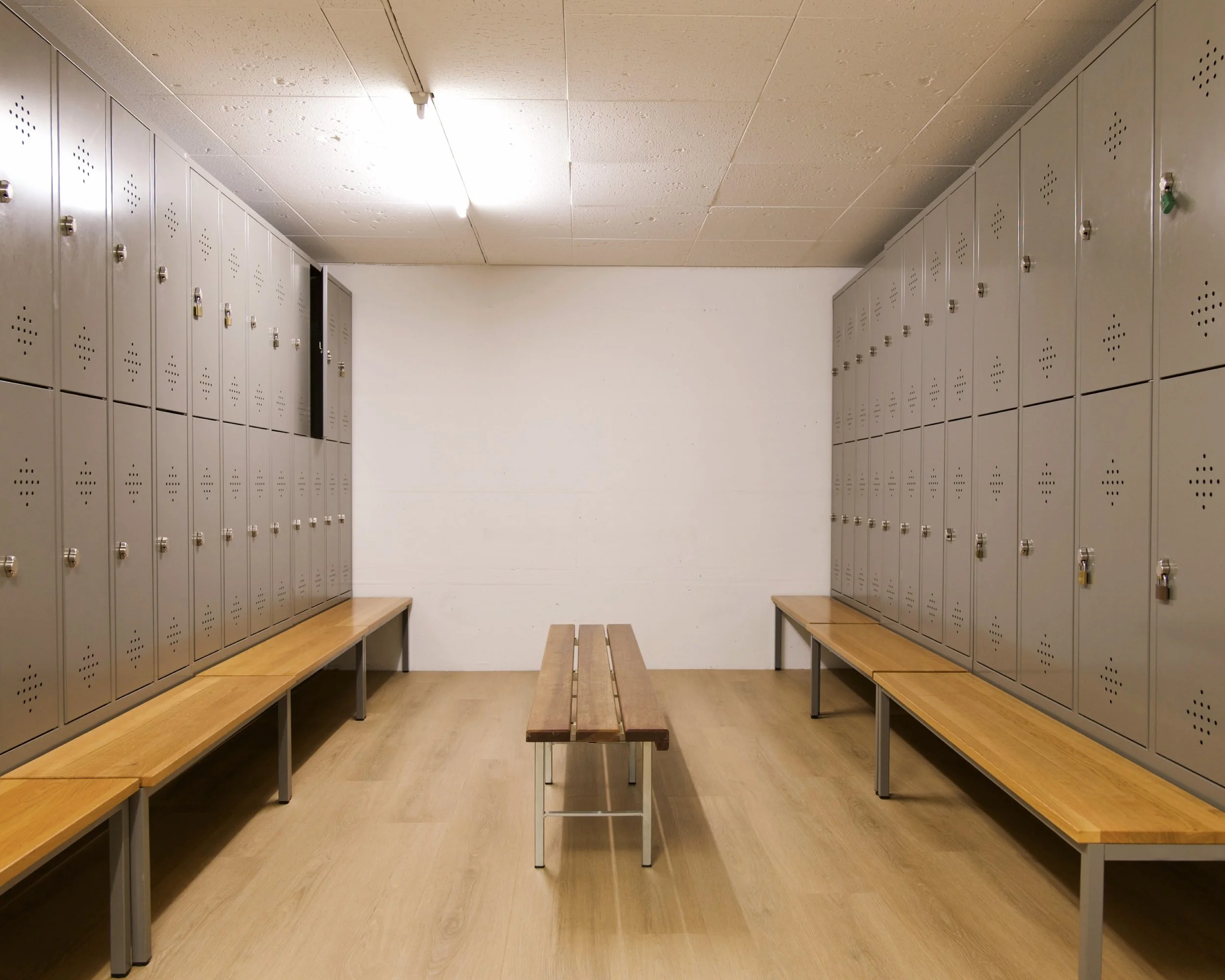 Ein Schulumkleideraum mit Spinds und Bänken, leere Umgebung.
