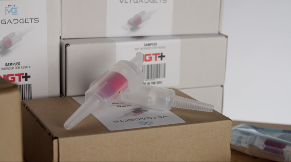 Two NGT+ adapters with red valves resting on a Vet Gadgets box