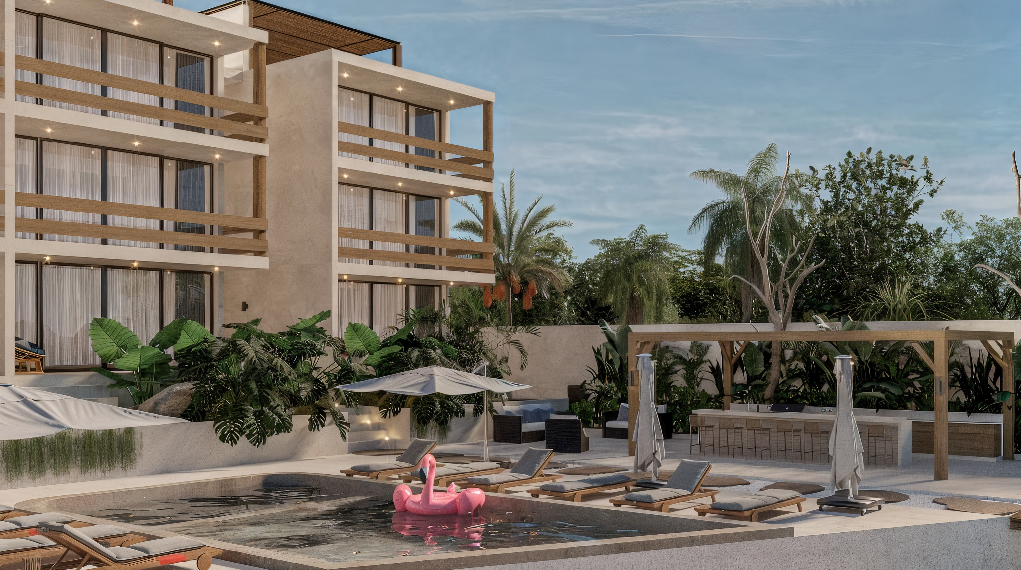 Piscina en un área de descanso con sillas y sombrillas, inflable en forma de cisne rosa y área de bar en un complejo de apartamentos, rodeado de plantas y árboles con cielo despejado.