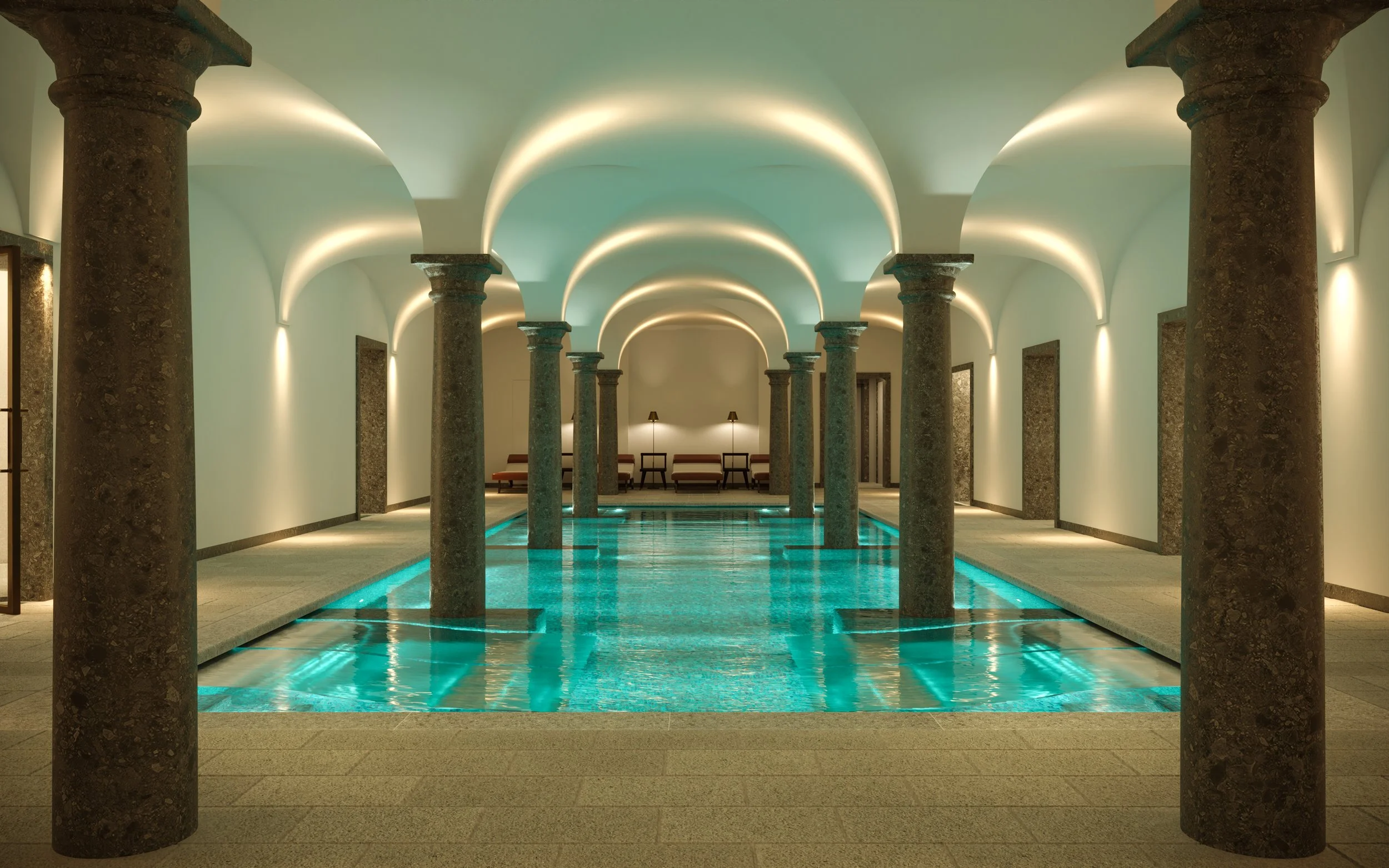 Indoor swimming pool area with stone columns, illuminated ceilings, and seating in the background.