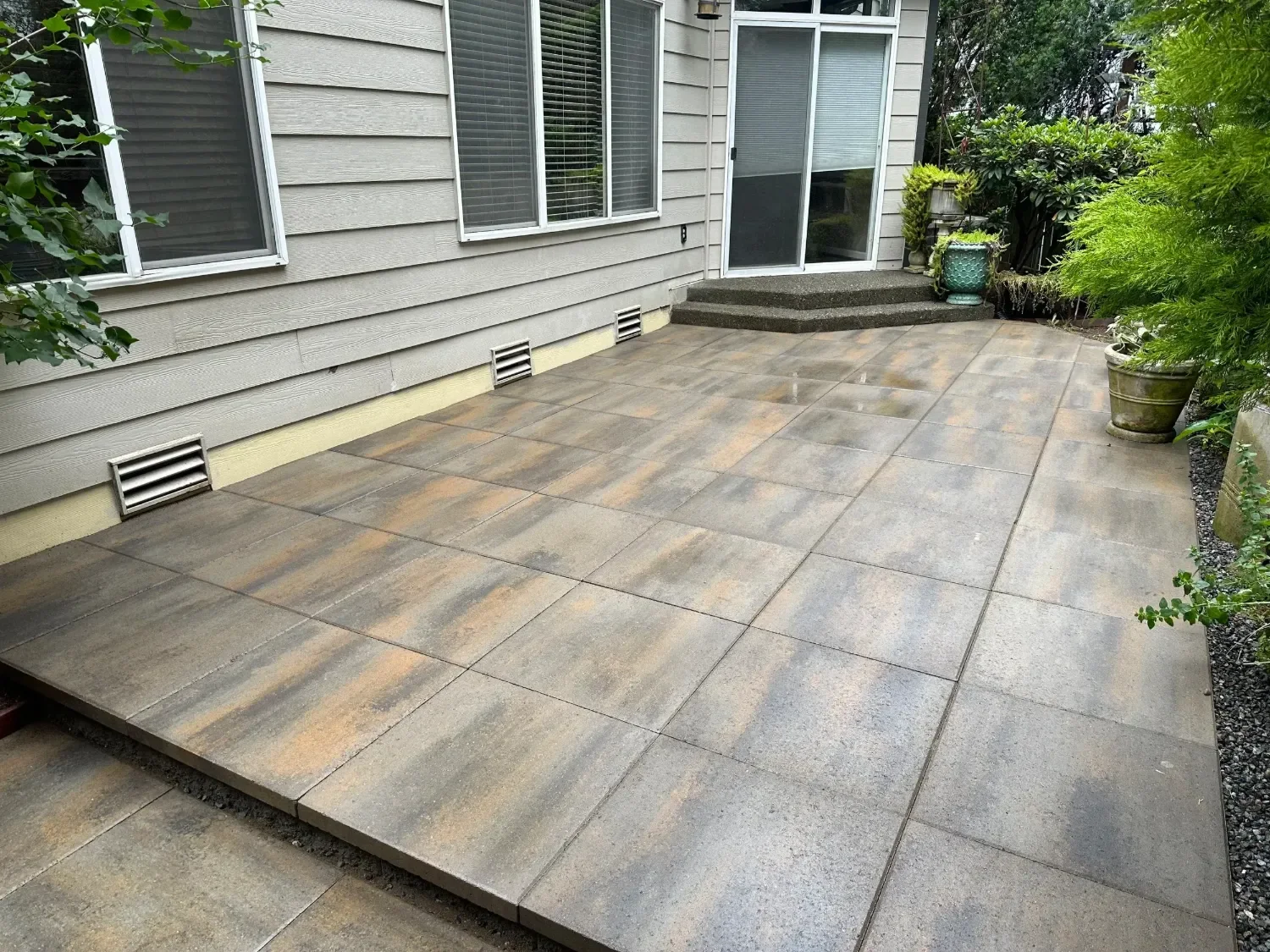 Large-format paver patio installation in Seattle, WA with multi-tone gray and brown pavers along the back entry of a Pacific Northwest home.