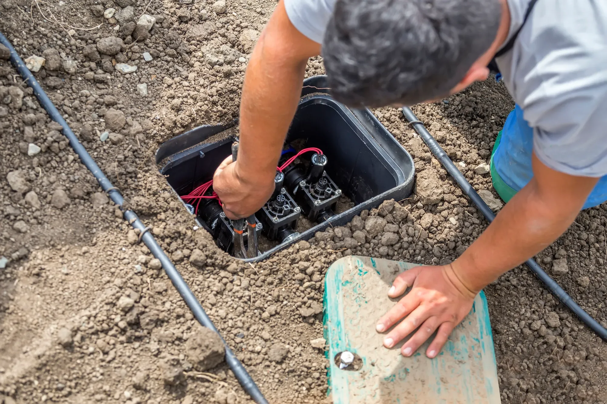 Technician installing underground irrigation components in Redmond, WA for long-term landscaping care