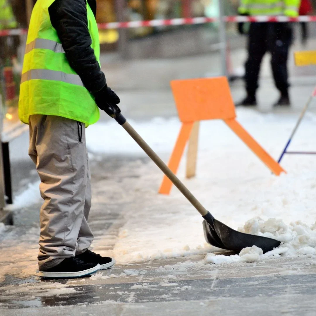 Snow removal crew clearing a sidewalk and pedestrian zone at a Kirkland commercial property