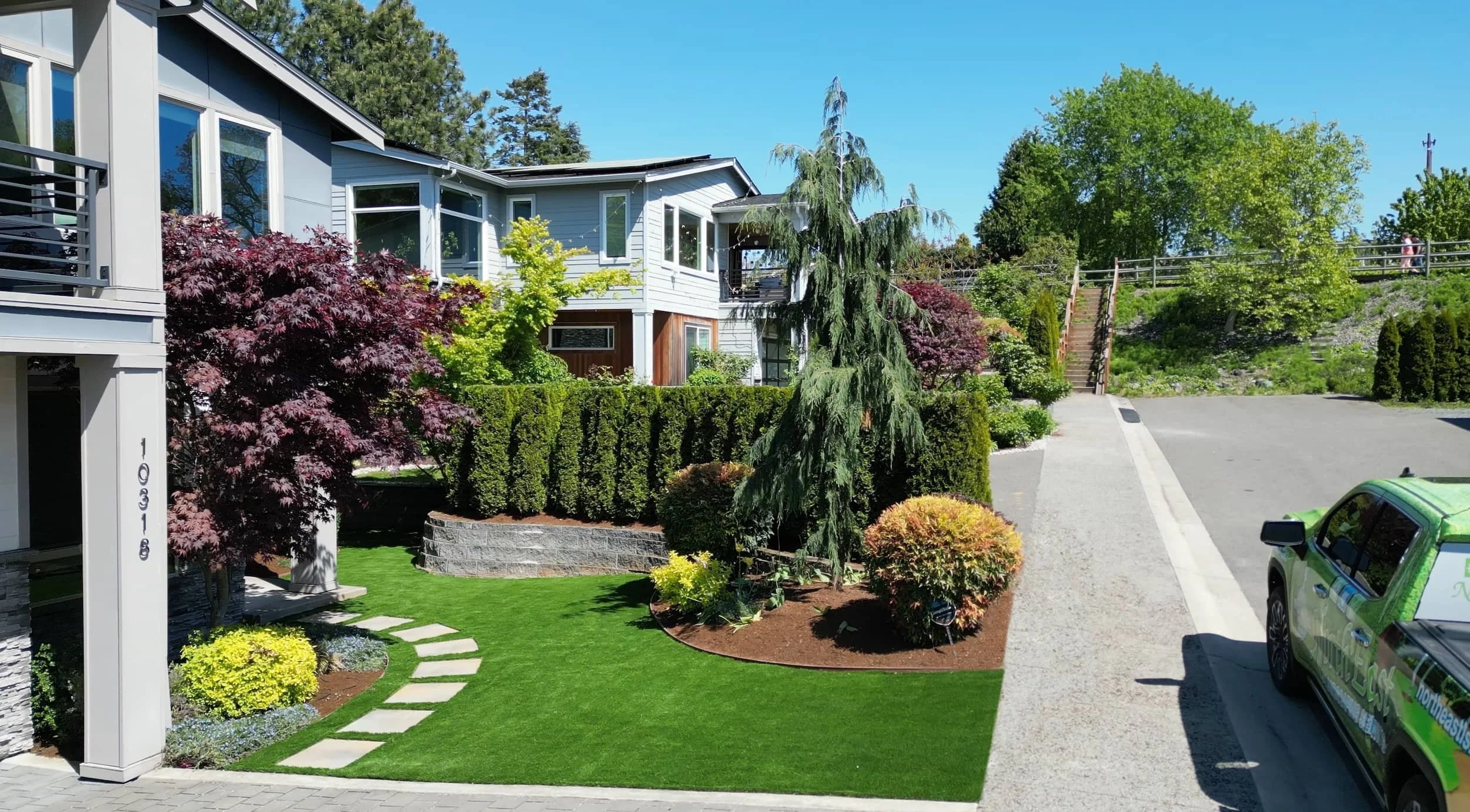 Front yard landscaping with manicured lawn, shrubs, trees, and walkway at a home in Seattle, WA