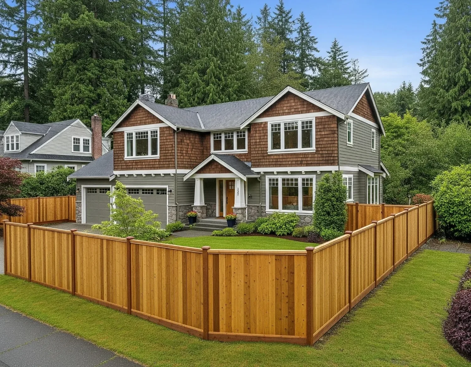 Residential landscaping project in Mercer Island, WA with manicured front lawn, planting beds, and wood privacy fencing around the property