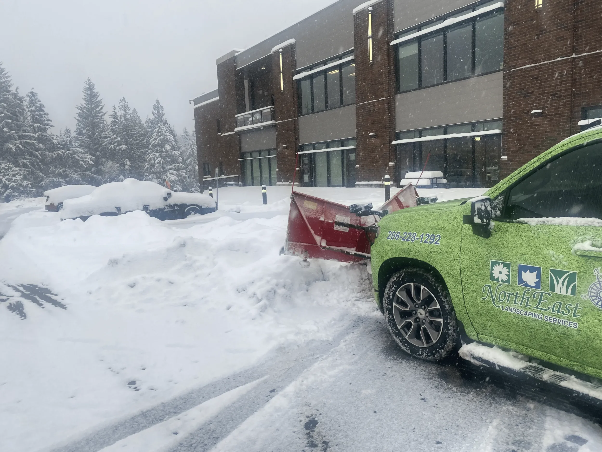 Commercial snow plowing service at a Kirkland, WA office building during a winter storm