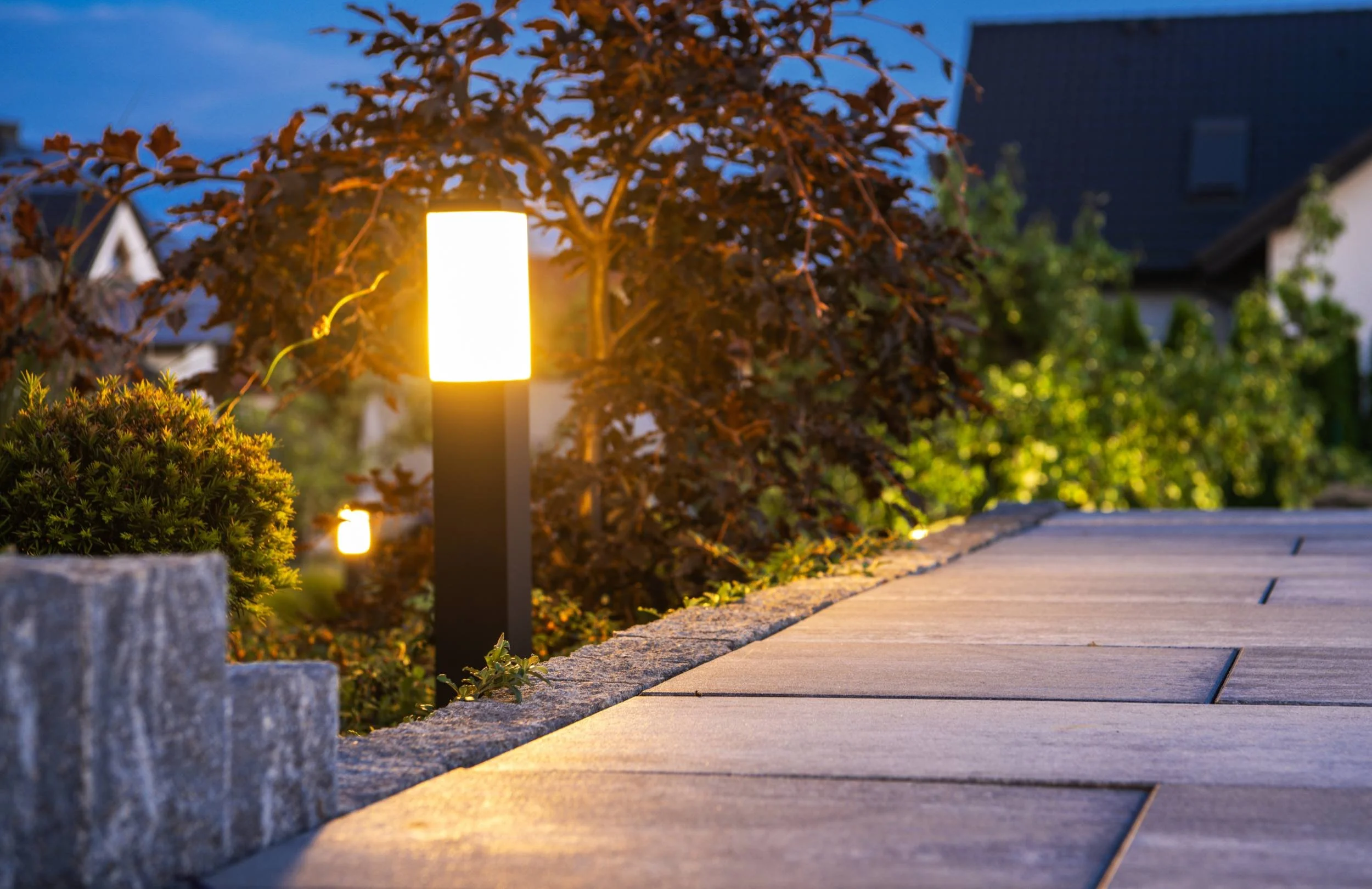 Custom outdoor lighting installed along a paver walkway and stone wall at a Sammamish, WA property