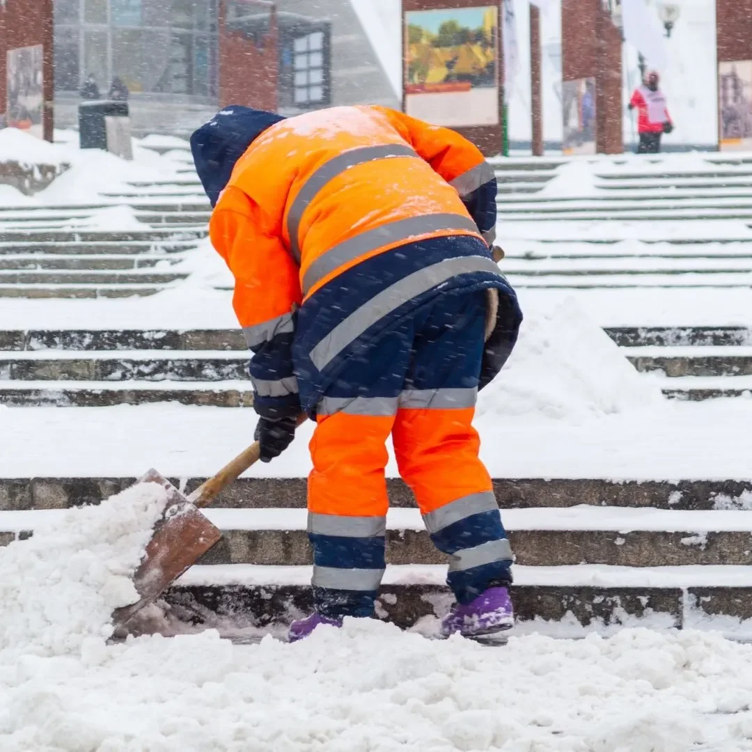 Snow removal worker shoveling commercial entry stairs in Bothell, WA during a winter storm