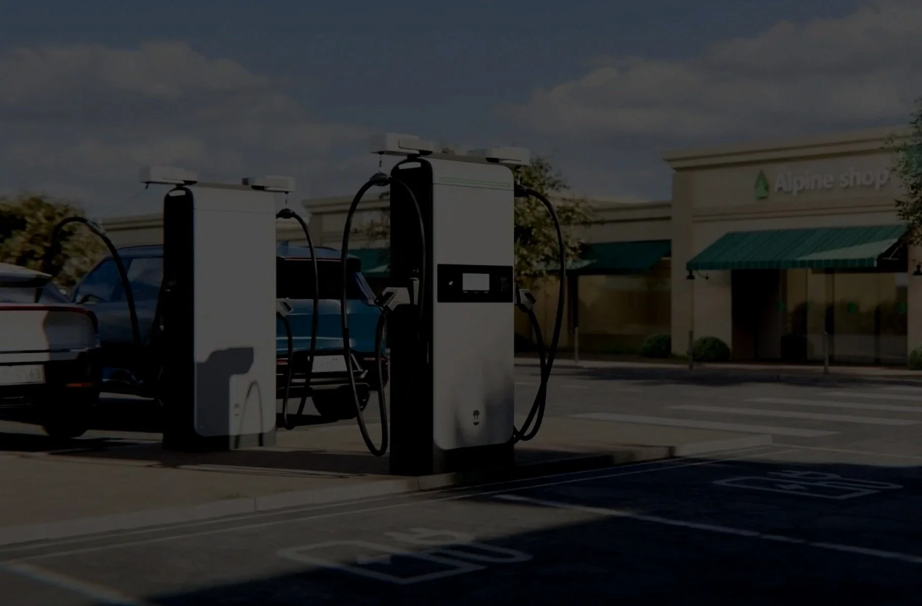 Electric vehicle charging station in a parking lot outside a shopping center with an Alpine Shop store in the background.