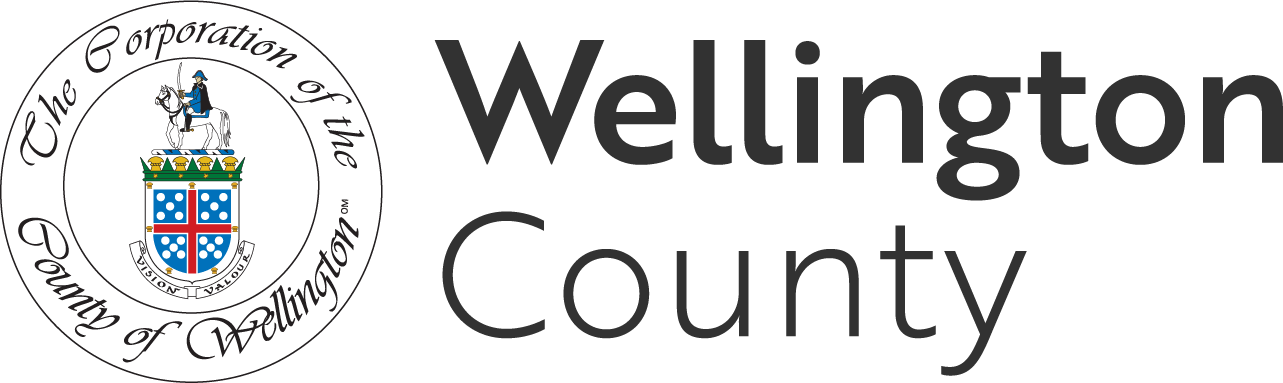 Logo of Wellington County featuring a shield with a blue background, white dots, and a red cross, topped with a crown, and surrounded by the text "The Corporation of the County of Wellington." To the right, the text "Wellington County" is displayed.